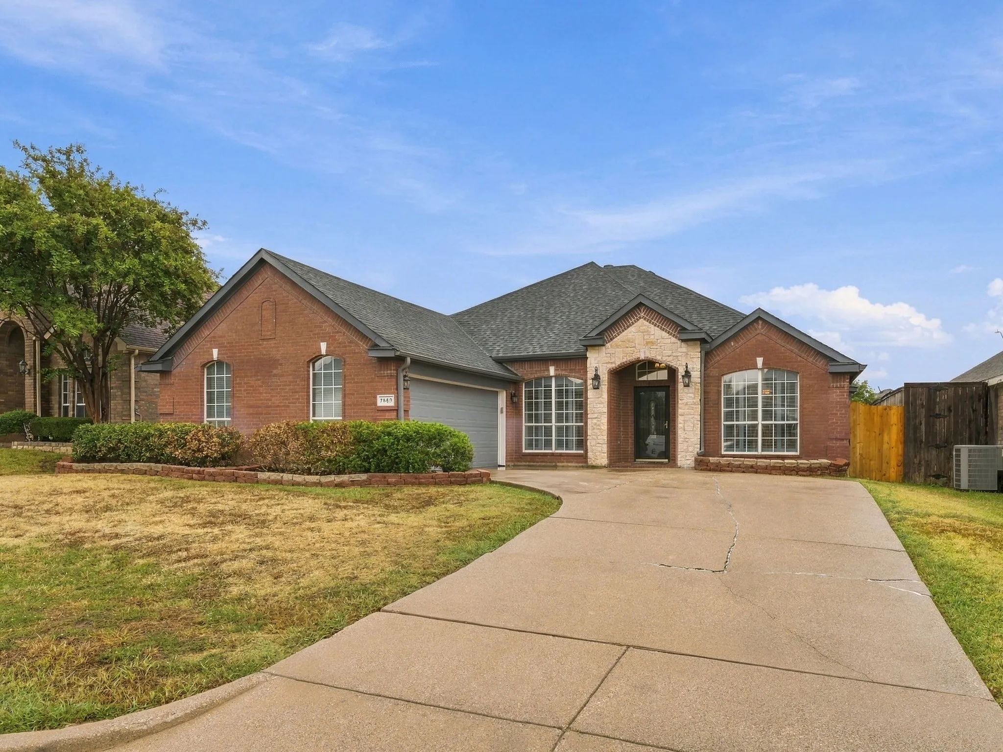 Brick exterior with stone accents, arched windows, and a segmented driveway