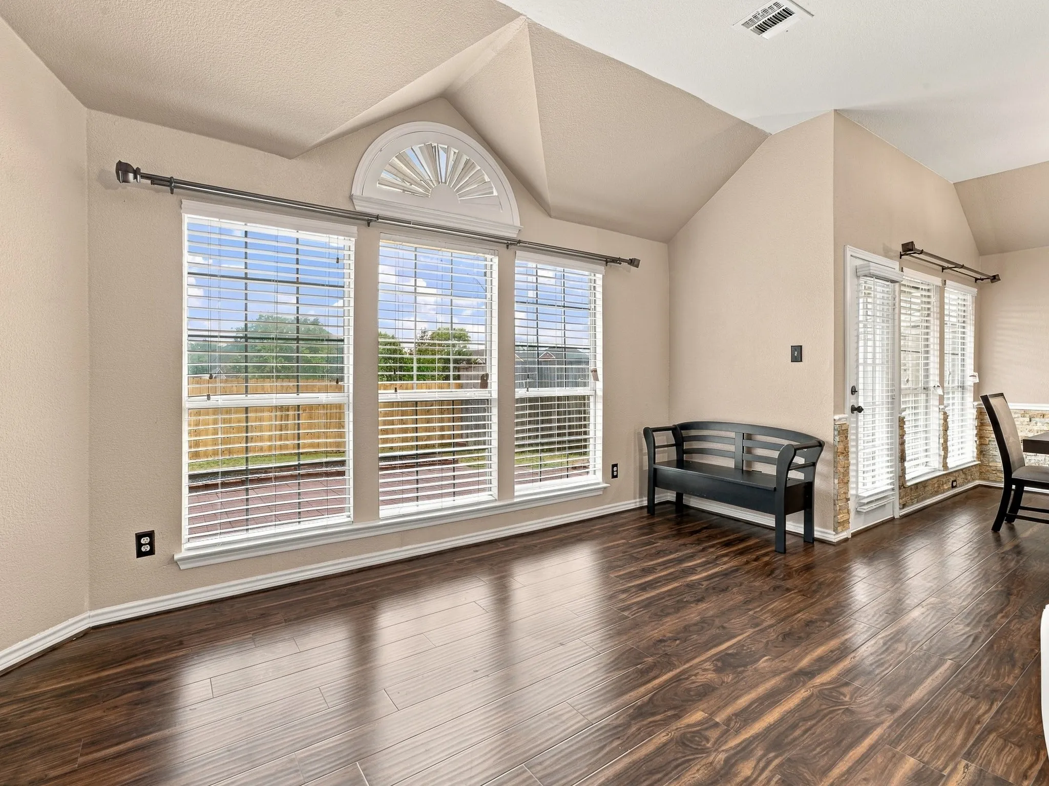 Vaulted ceiling, wood-finish flooring, bay window with arched transom, and extensive natural light
