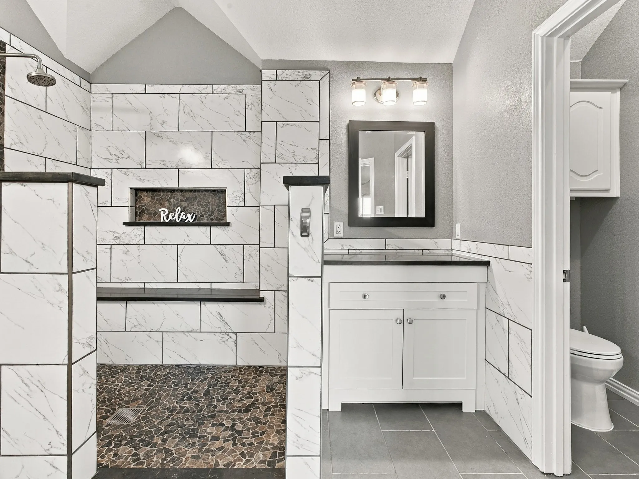 Walk-in shower with pebble tile flooring and a built-in bench