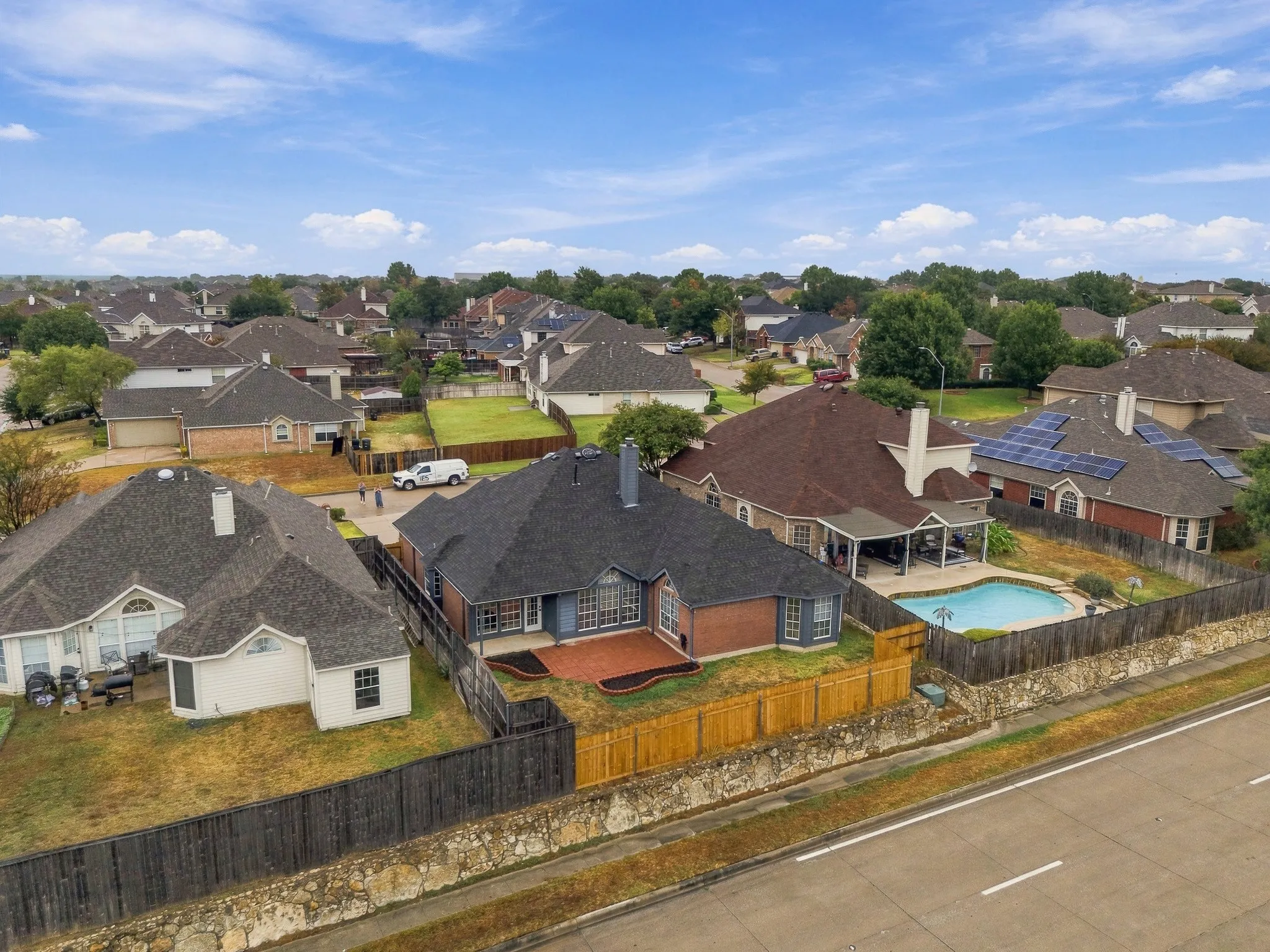 Brick exterior with an attached garage, backyard swimming pool, and wood privacy fencing