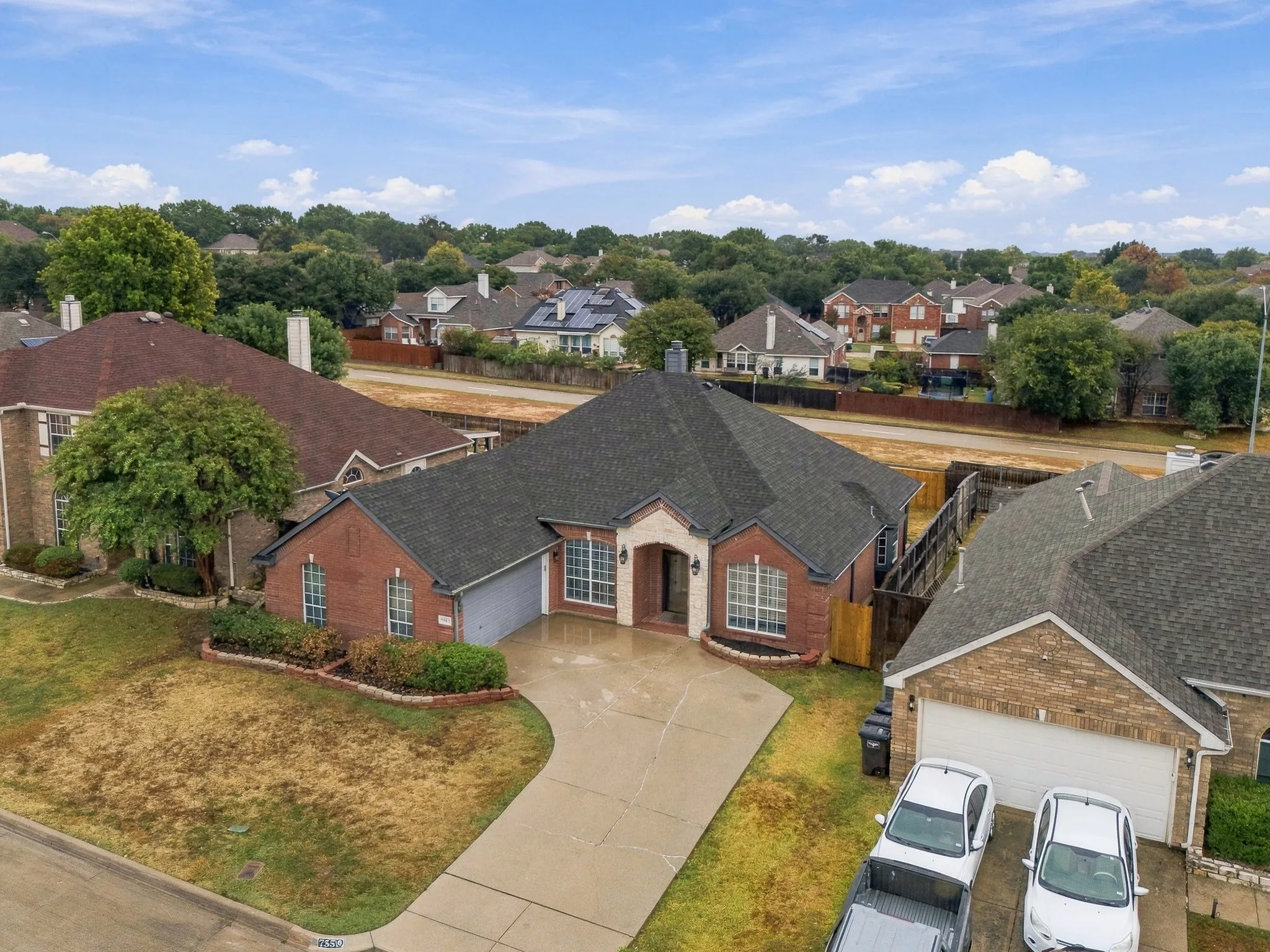 Red brick exterior with stone accents, attached garage, and landscaped front yard