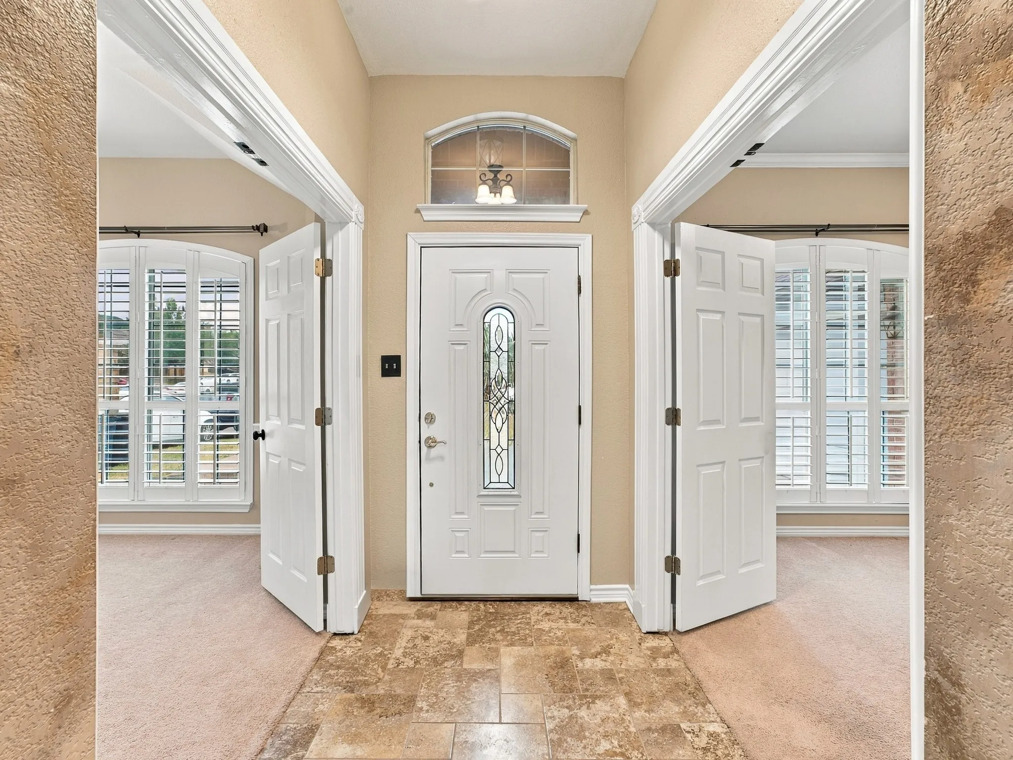 Entryway featuring a decorative glass front door, transom window, and tiled flooring