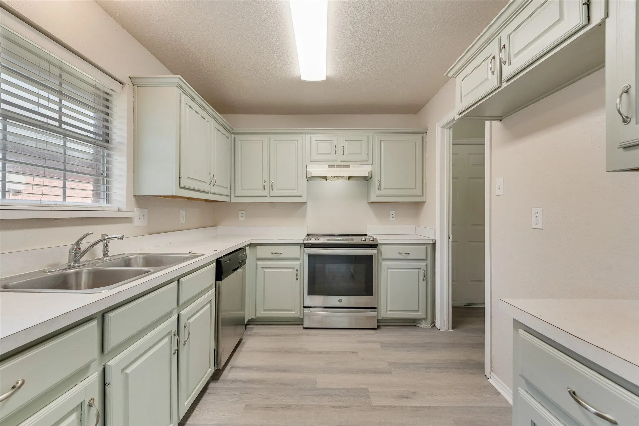 Kitchen featuring light-colored cabinetry, stainless steel range, and wood-finish flooring