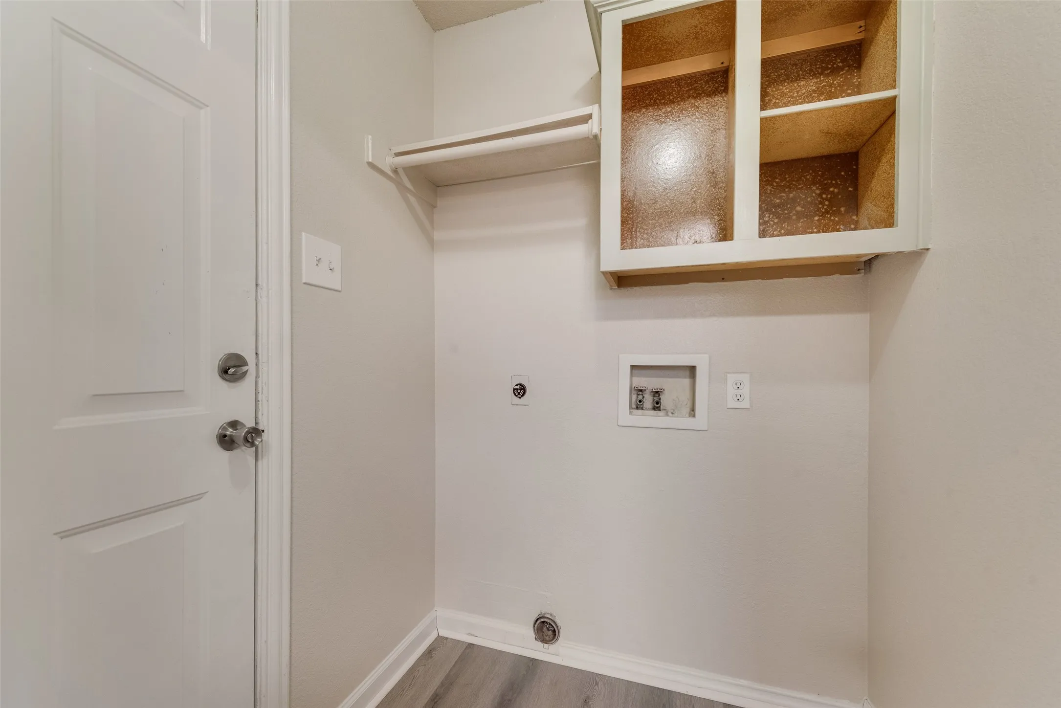 Laundry area with wood-finish flooring, overhead shelving, and built-in cabinetry