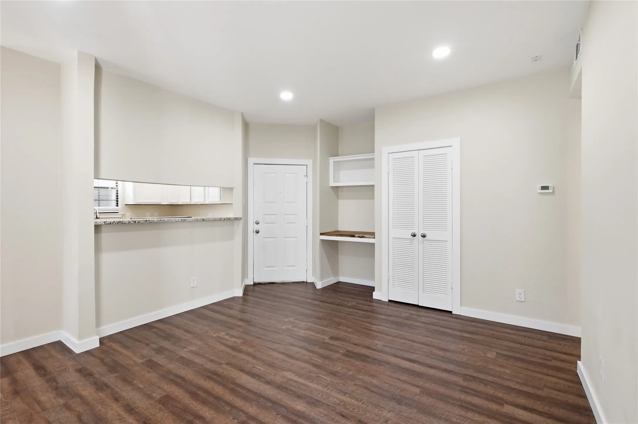 Wood-finish flooring throughout, recessed lighting, and built-in desk with shelving