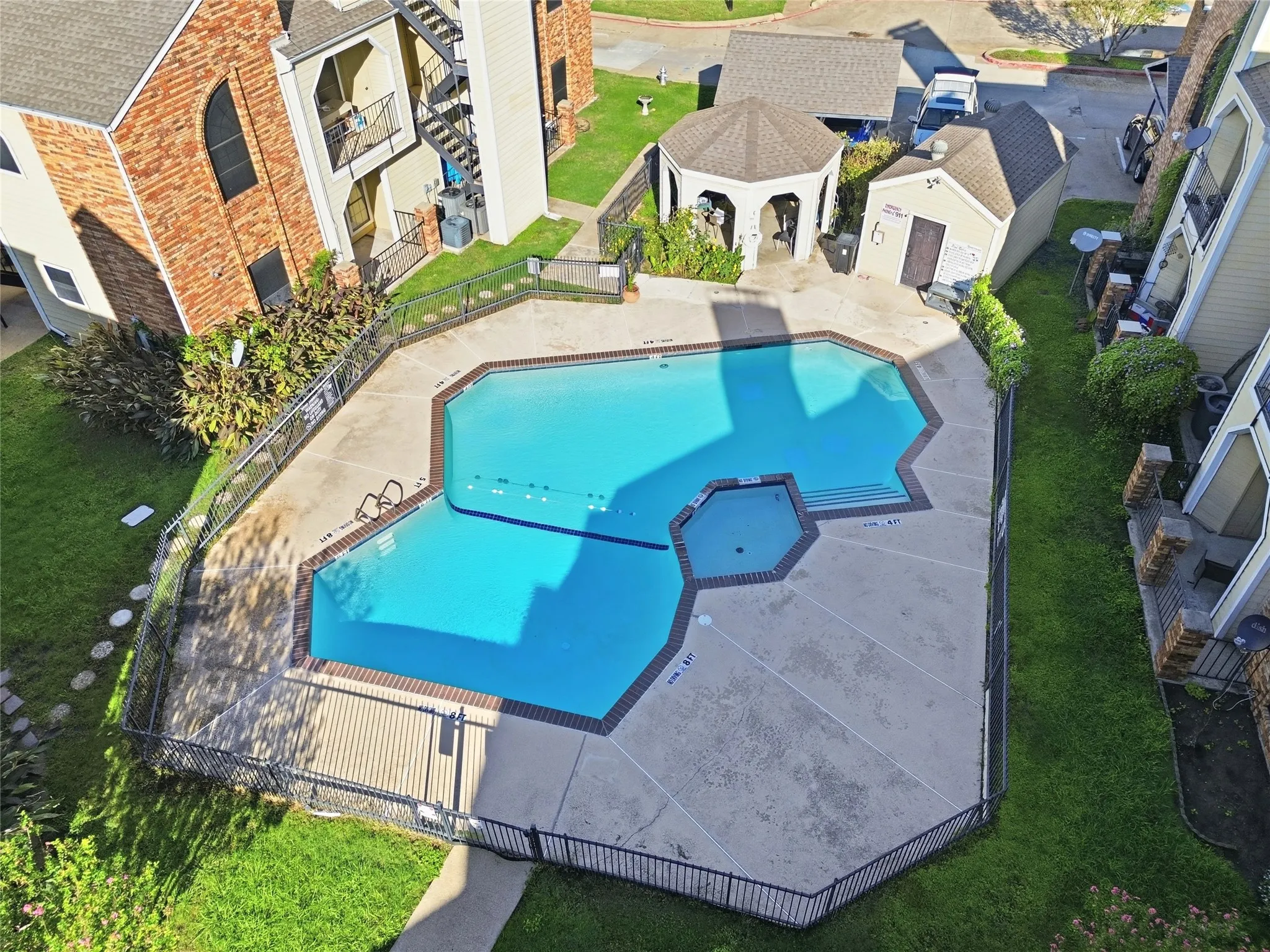 Fenced swimming pool with integrated spa and surrounding concrete decking