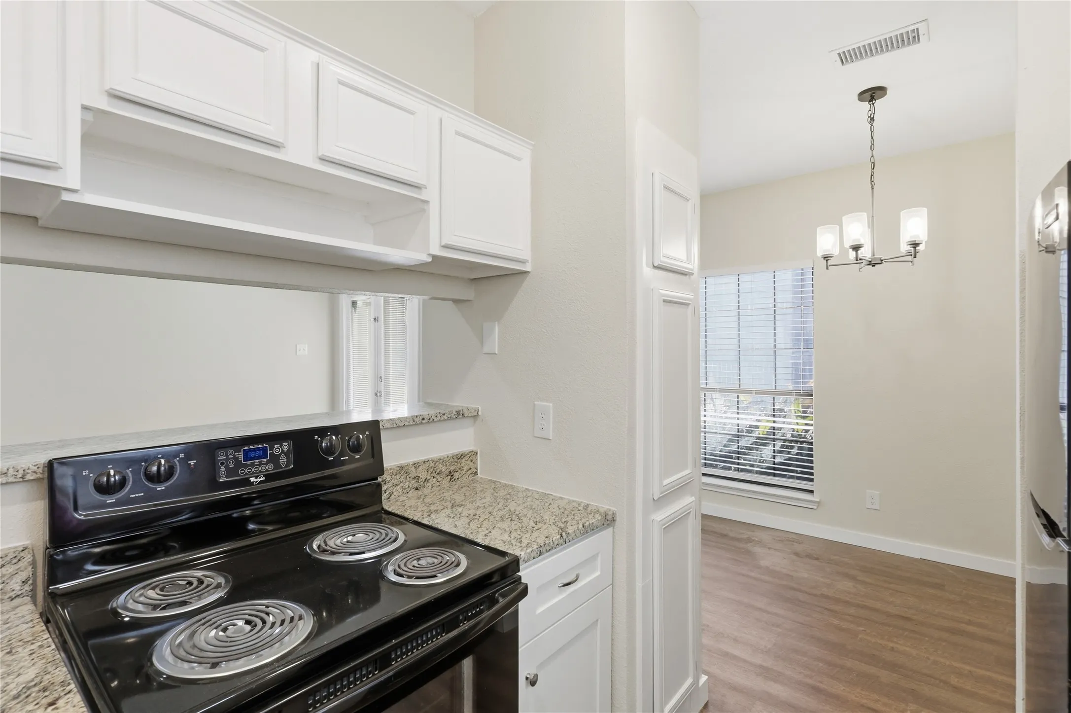 White cabinetry, granite-finish countertops, and wood-finish flooring