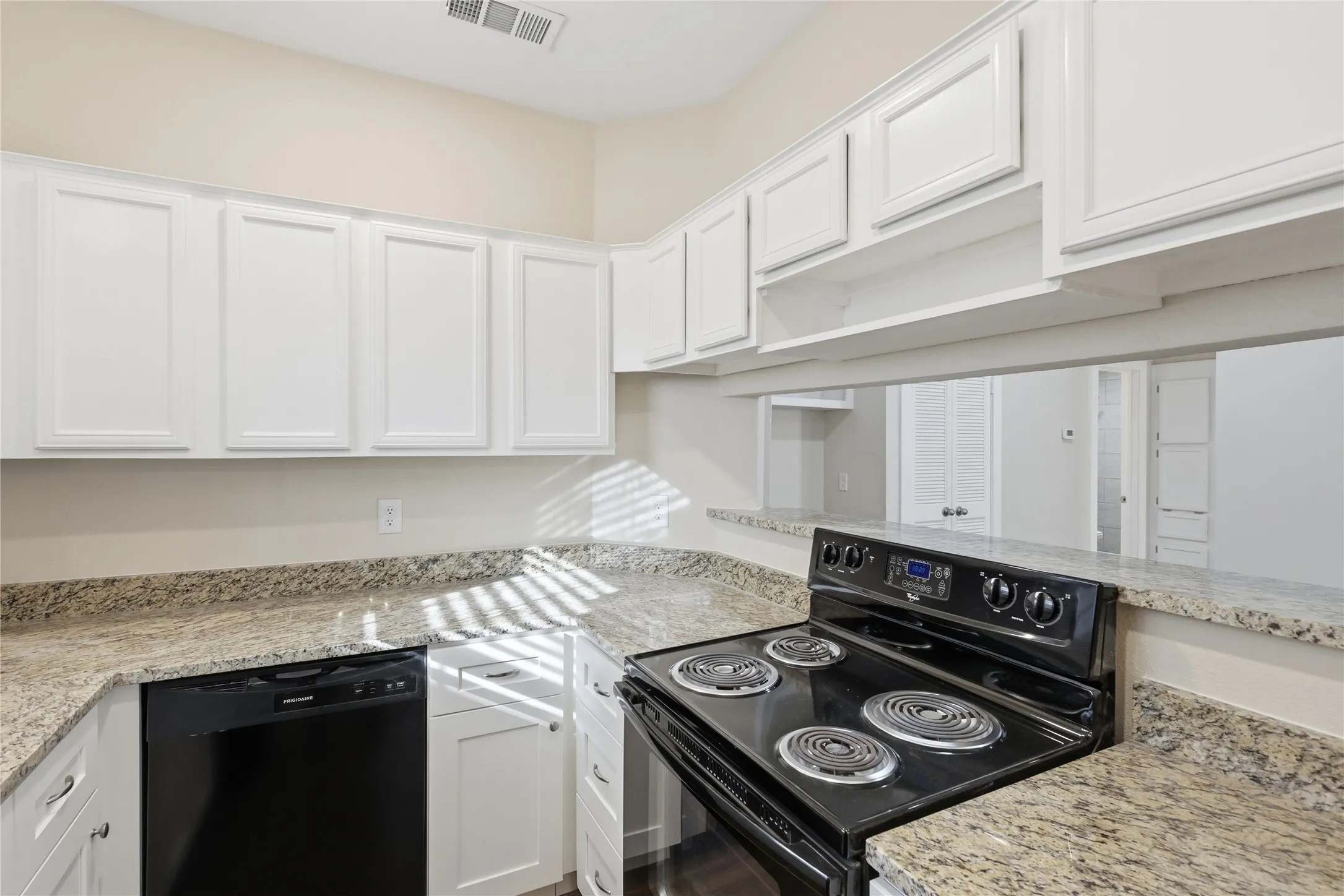 Kitchen featuring white cabinetry, granite countertops, black electric range, and black dishwasher