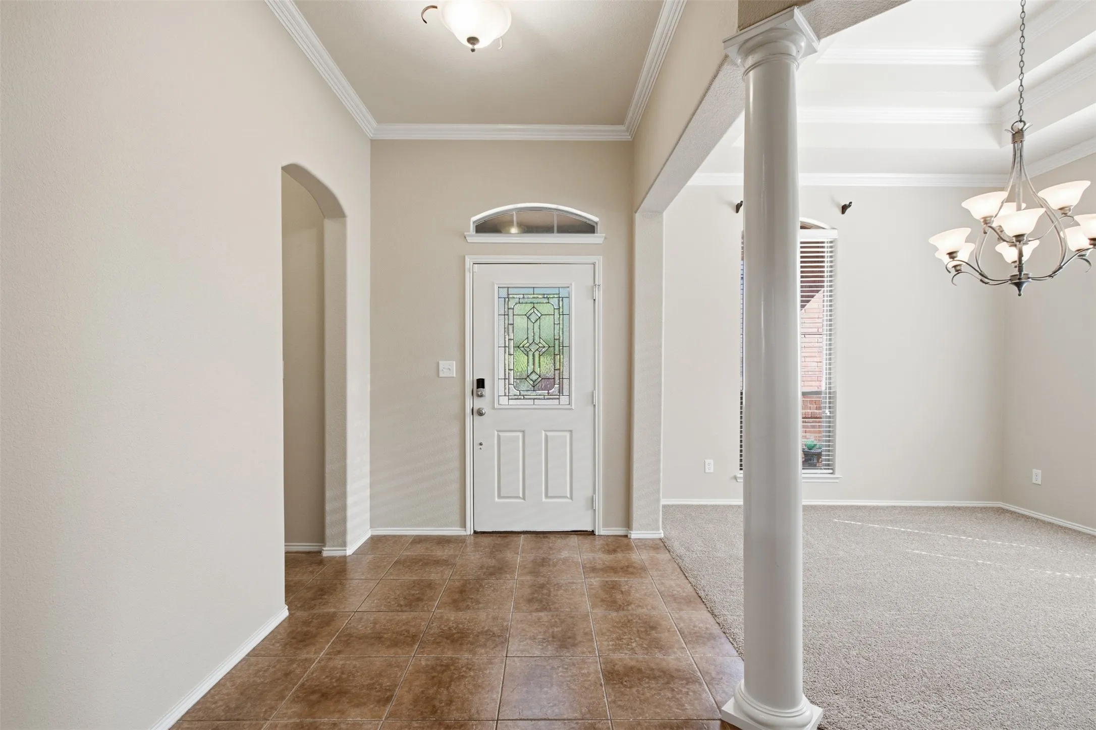 Tiled entryway with decorative glass door and transom window