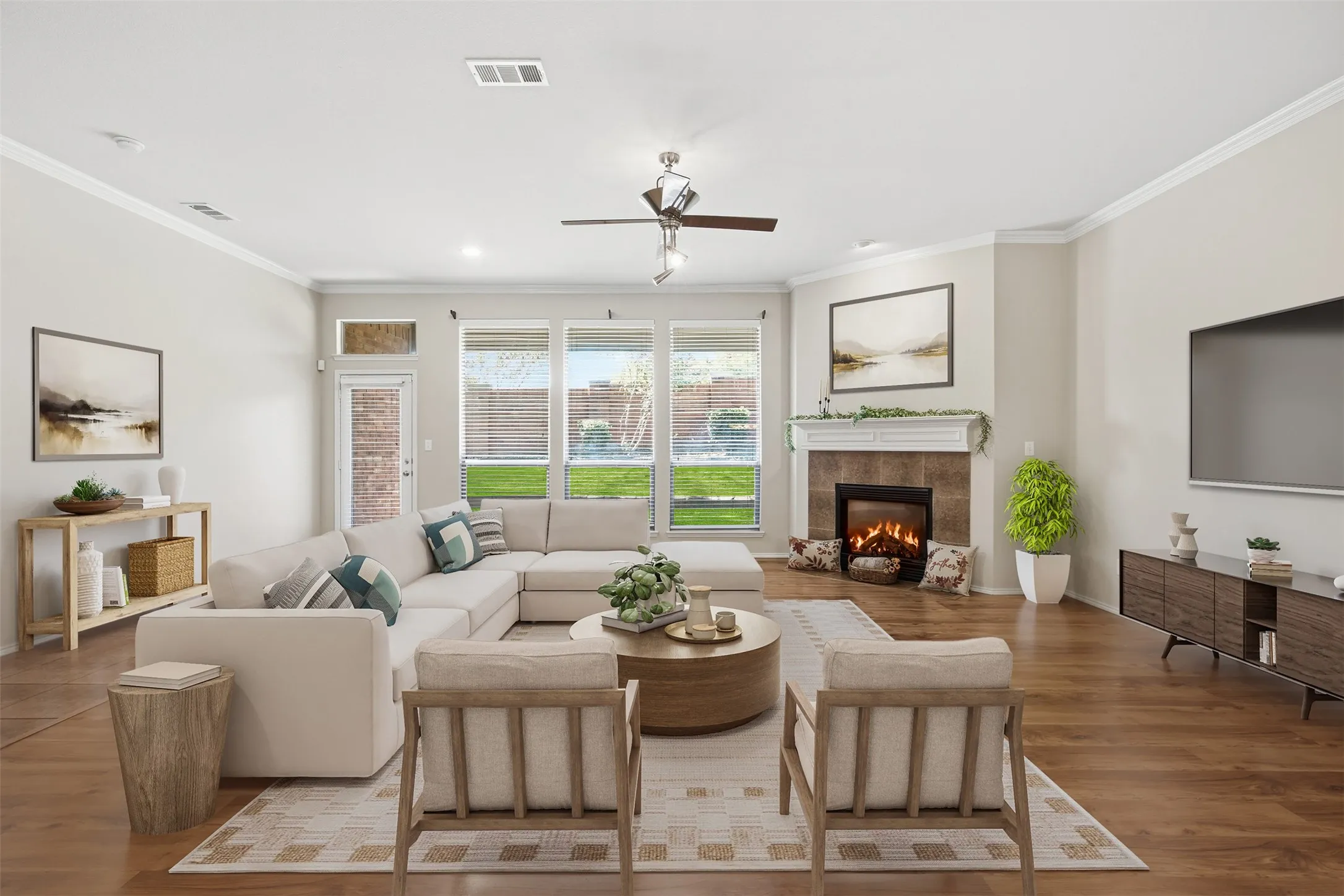 Spacious living area featuring wood-finish flooring, a corner fireplace with a tiled surround and mantel, and crown molding. Virtually staged.