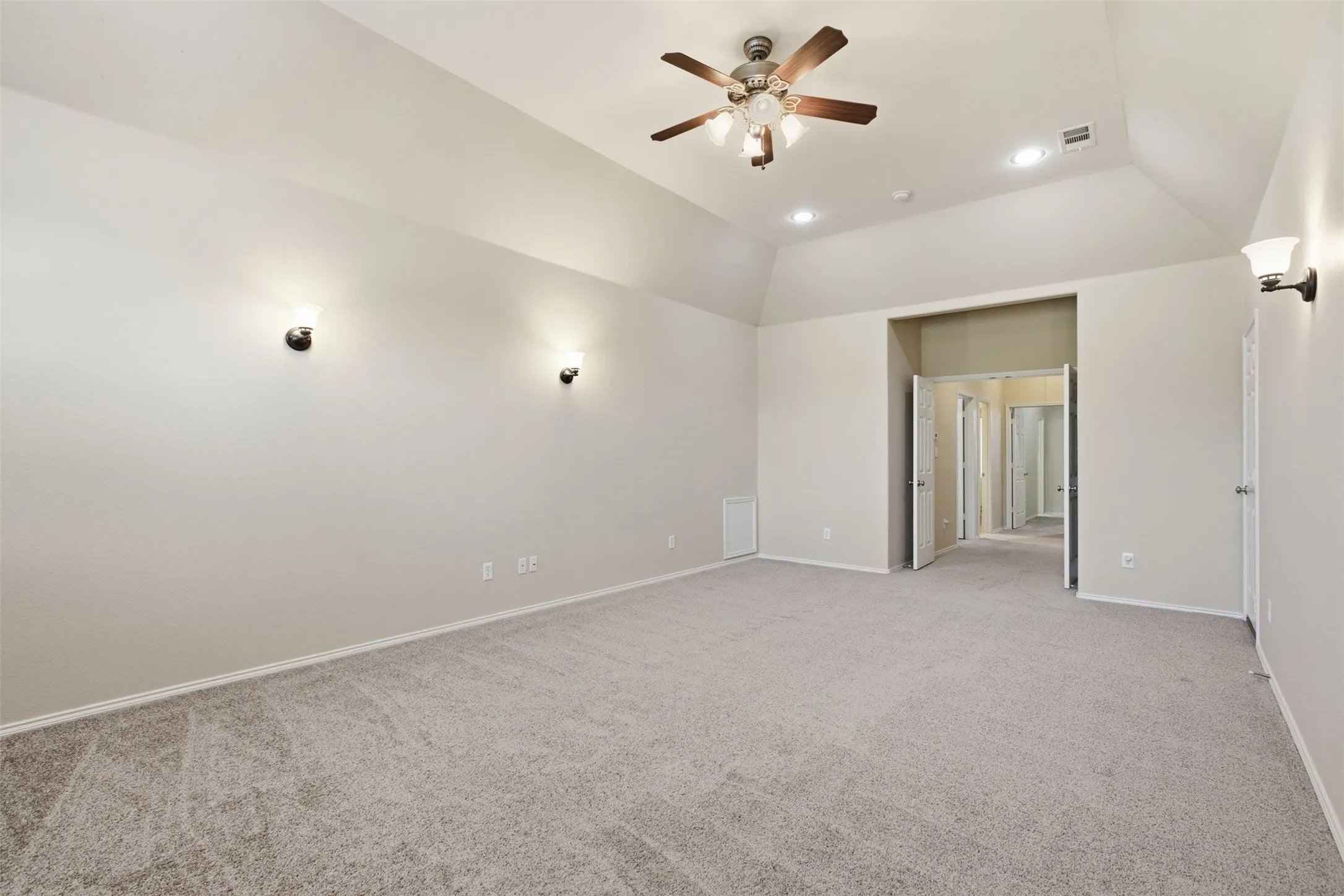 Vaulted ceiling with a ceiling fan, recessed lighting, and wall sconces