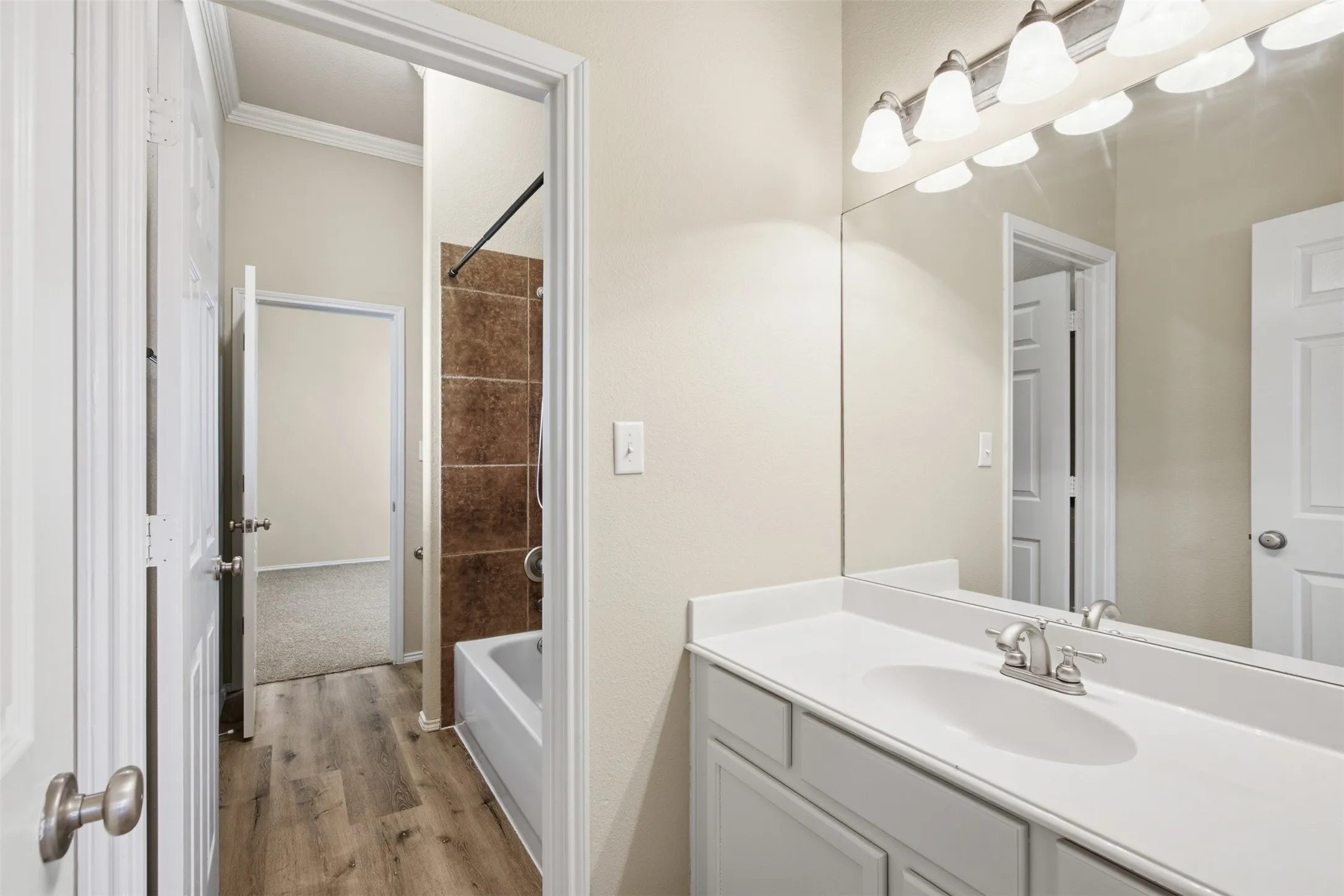 Vanity with an integrated sink, brushed nickel faucet, large wall mirror, and a five-light fixture