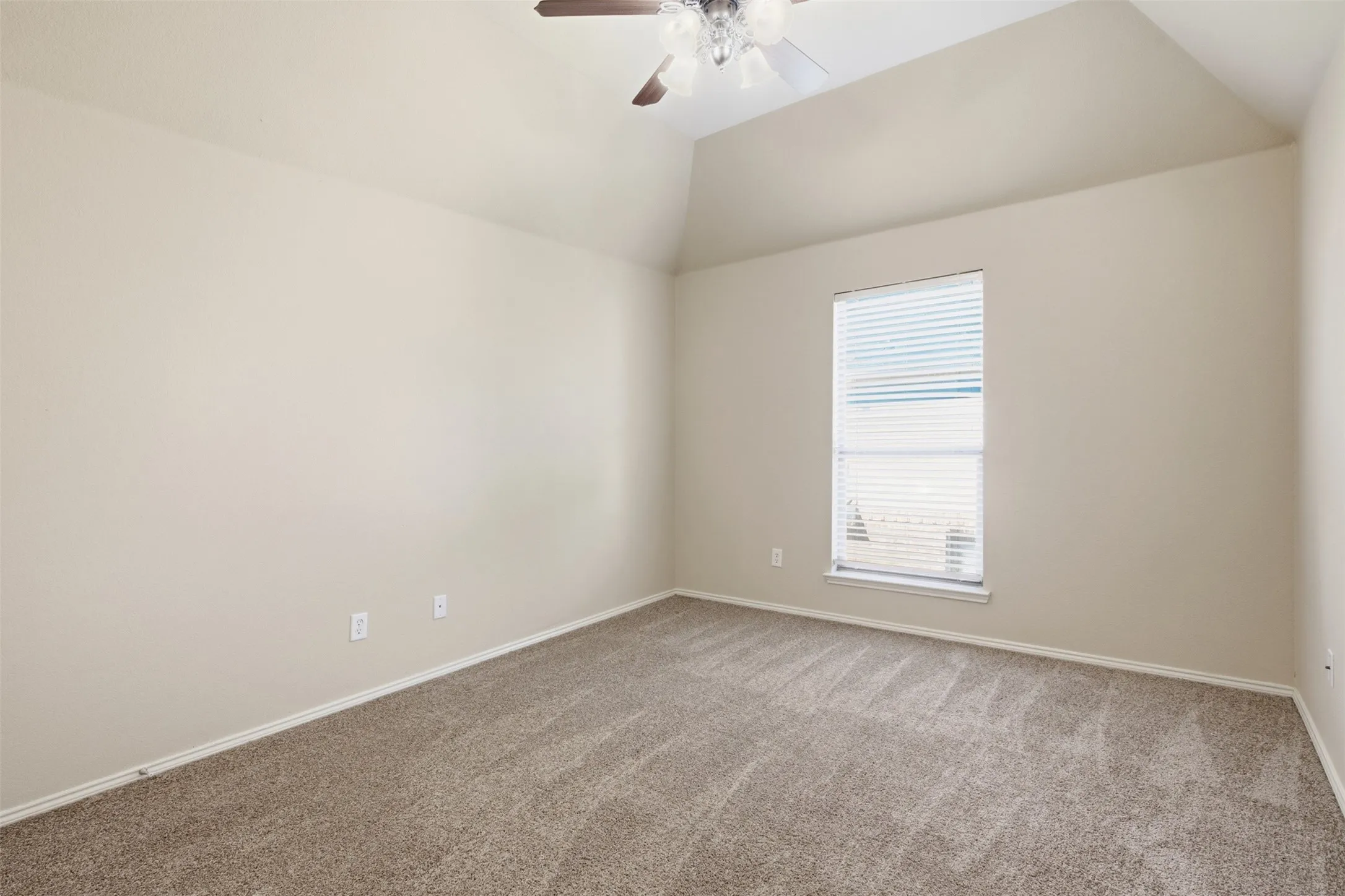 Vaulted ceiling with an attached ceiling fan, neutral tone carpeting, and a window with blinds