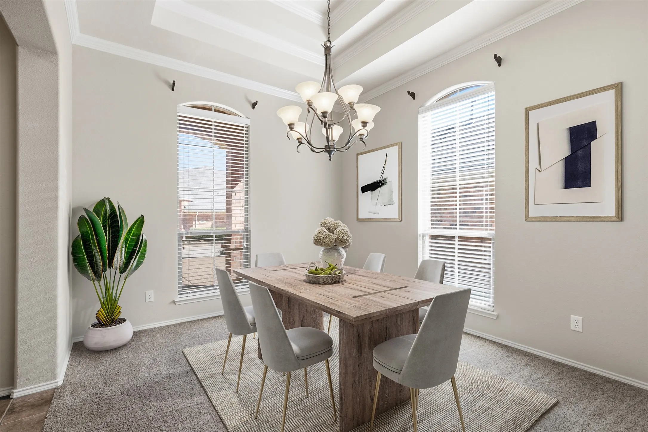 Tray ceiling with crown molding, arched window frames, chandelier lighting, and carpet flooring. Virtually staged