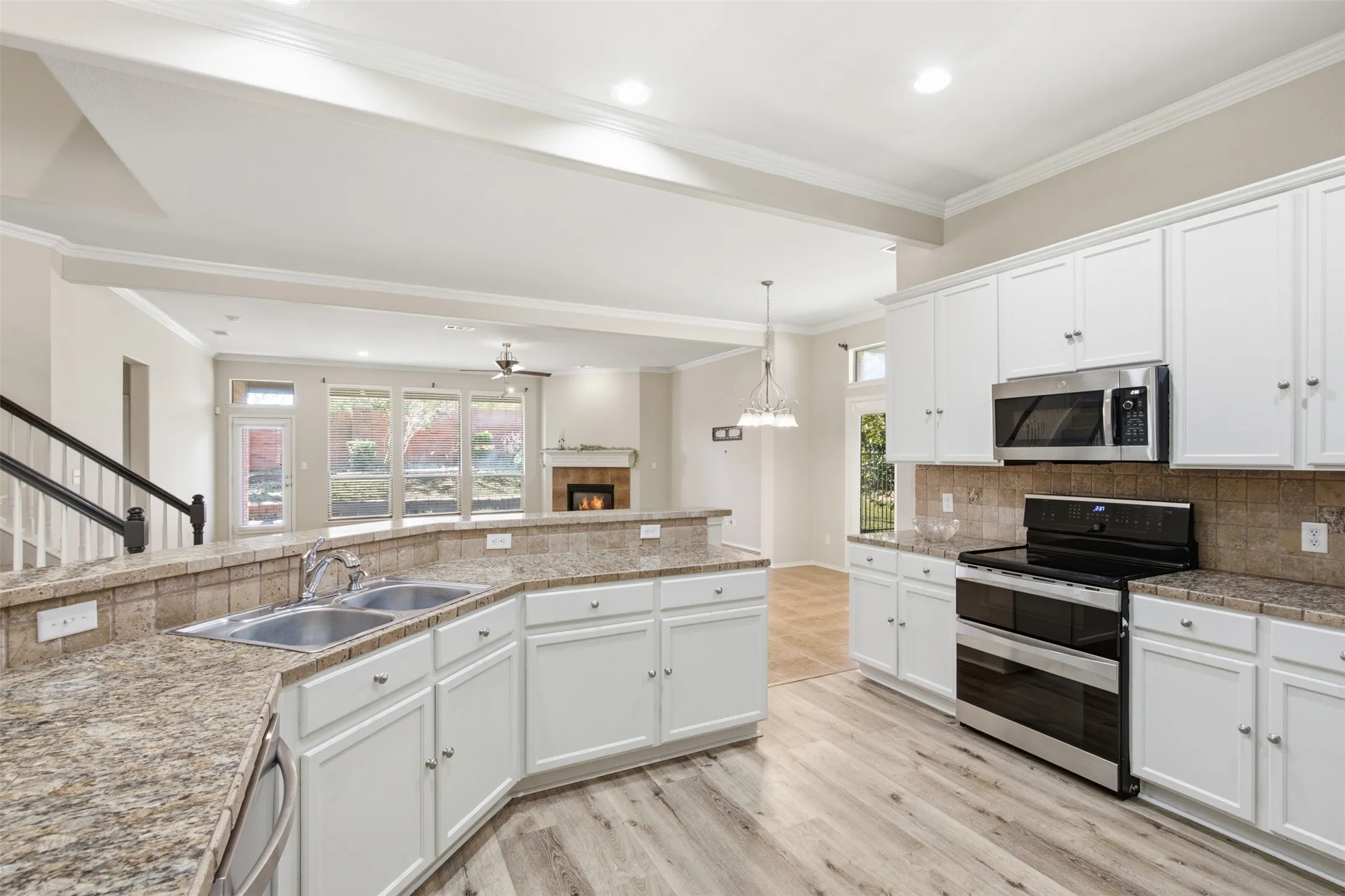 Kitchen featuring white cabinetry, stainless steel appliances, a double basin sink, and wood-finish flooring