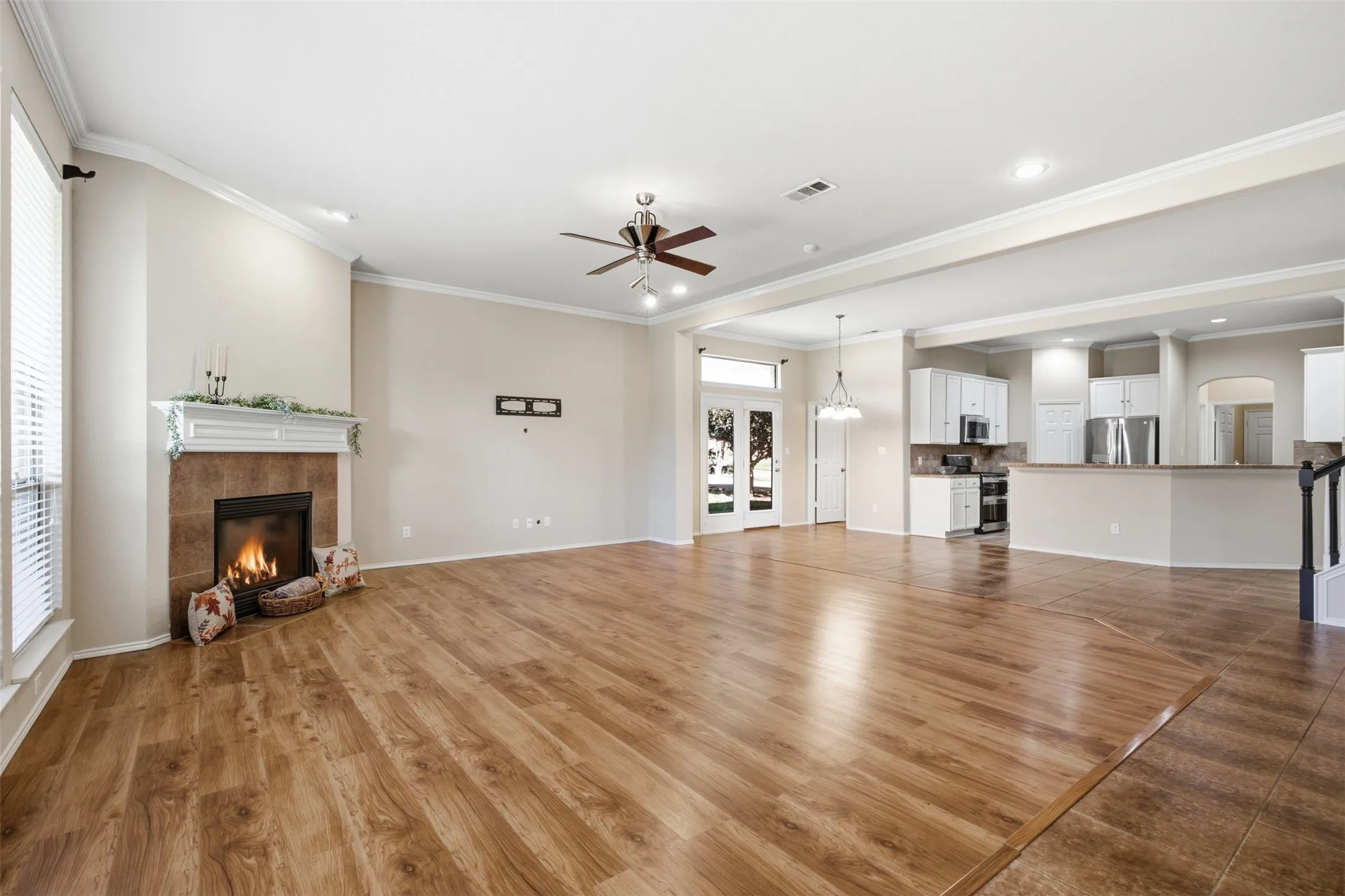 Spacious interior featuring wood-finish flooring, a tile-surround fireplace with a white mantel, and an open-concept layout