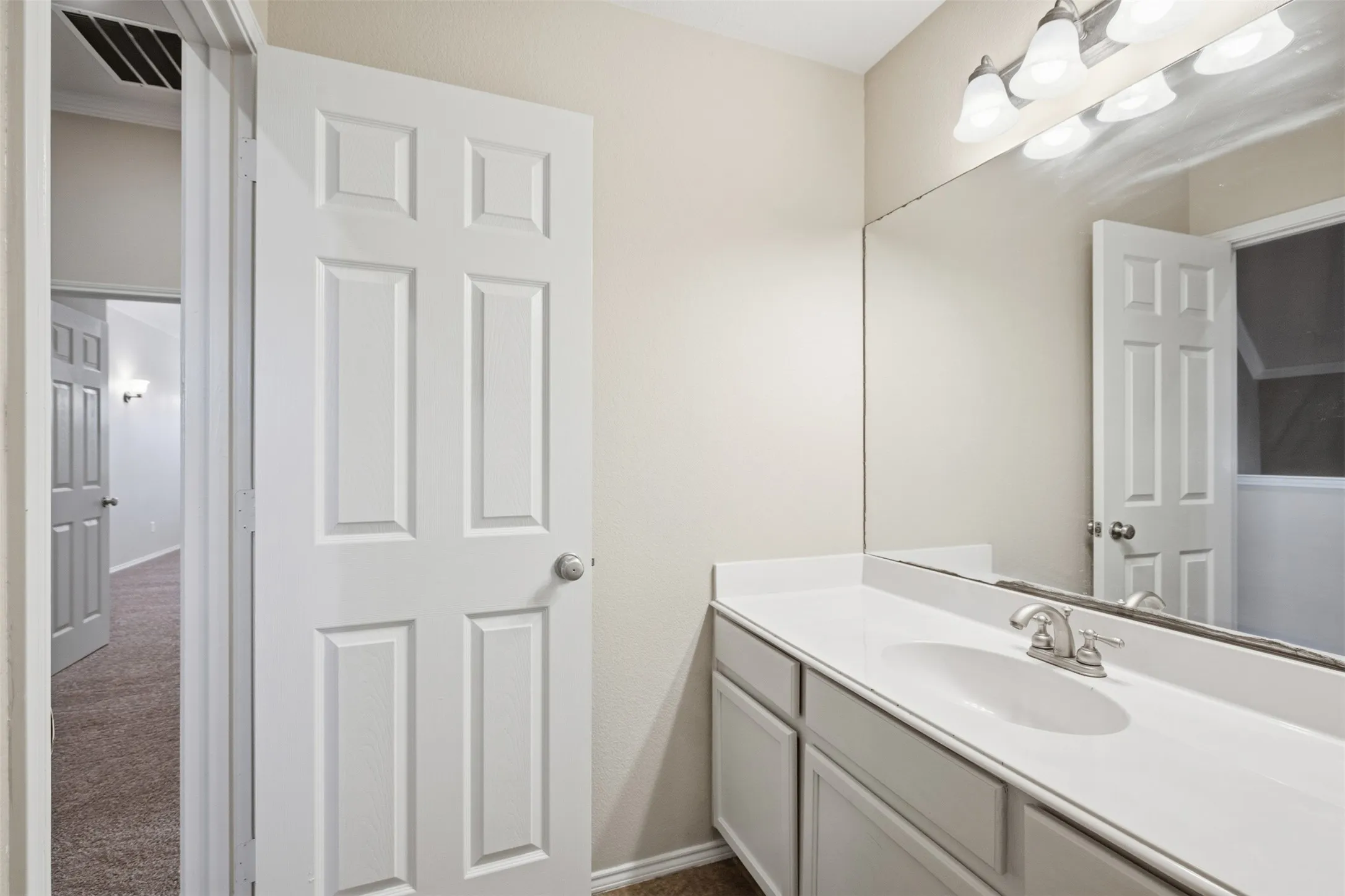 Vanity with integrated sink, brushed nickel faucet, full-width mirror, and a three-light fixture