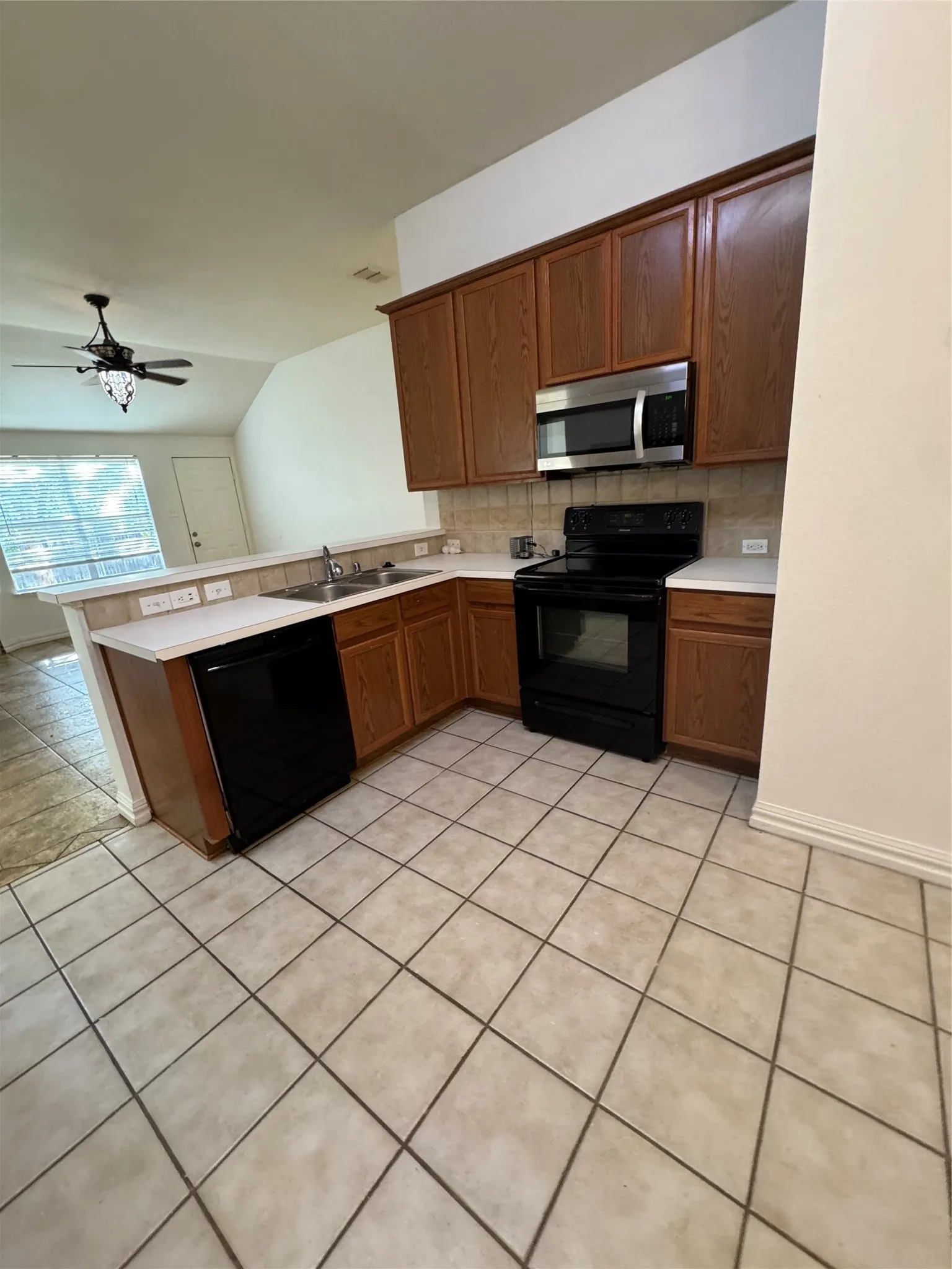 Kitchen featuring wood cabinetry, white countertops, tile flooring, and stainless steel microwave