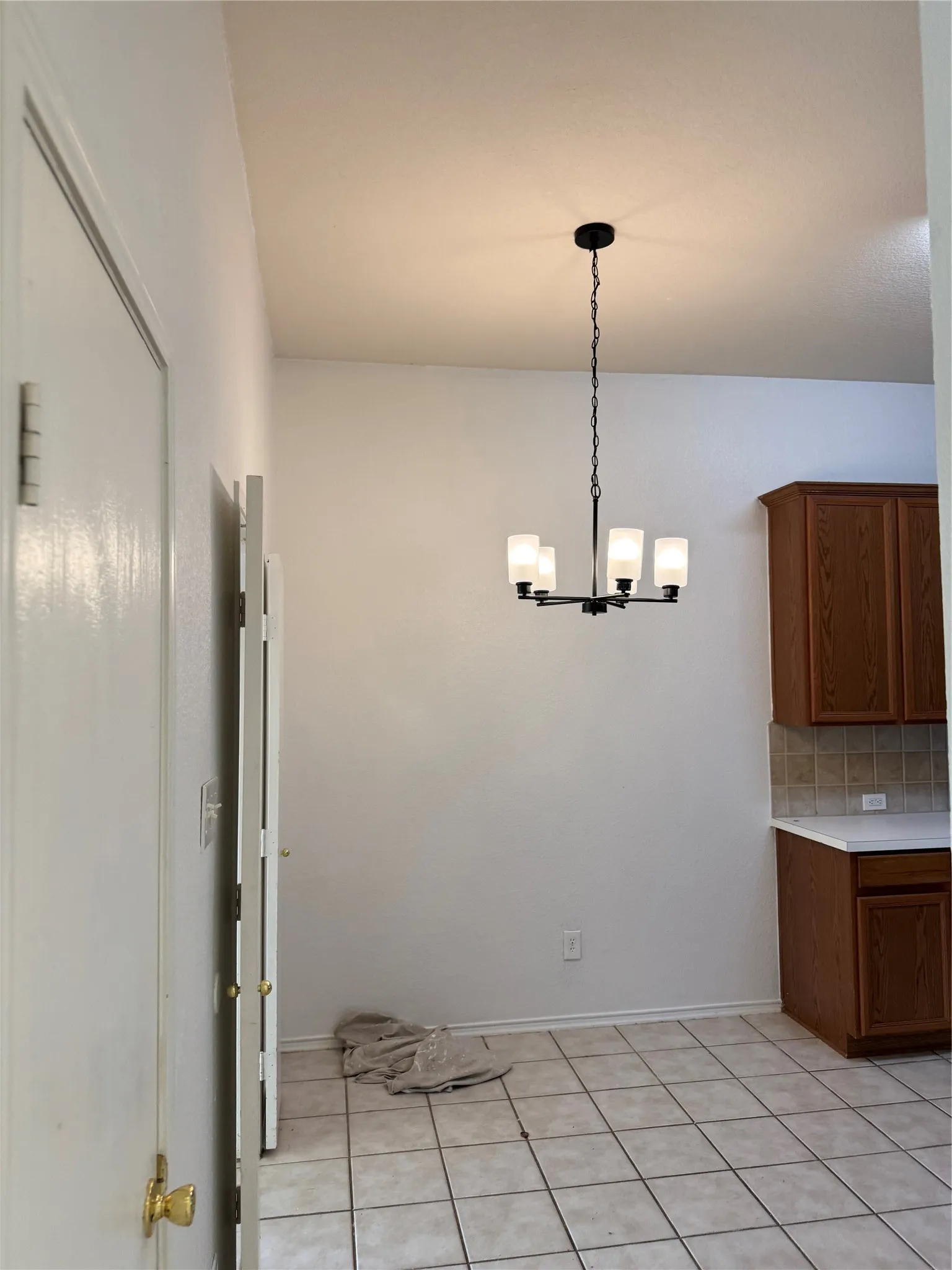 Kitchenette with tiled flooring, wood-finish cabinetry, and a modern chandelier