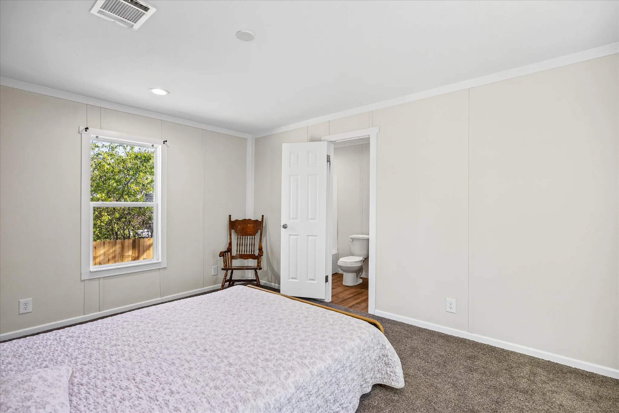 Carpeted room with white panel walls, crown molding, and a white framed window