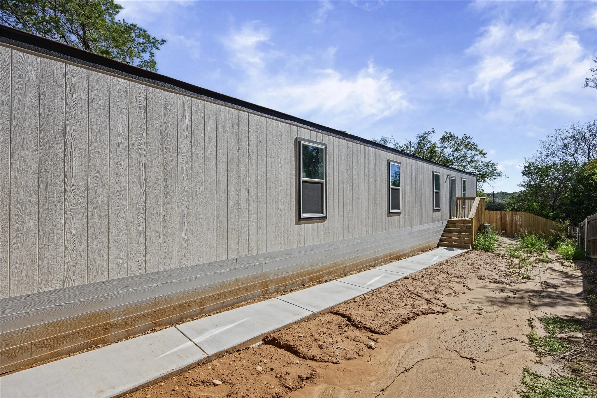 Light-colored vertical siding with multiple windows and a wooden exterior staircase