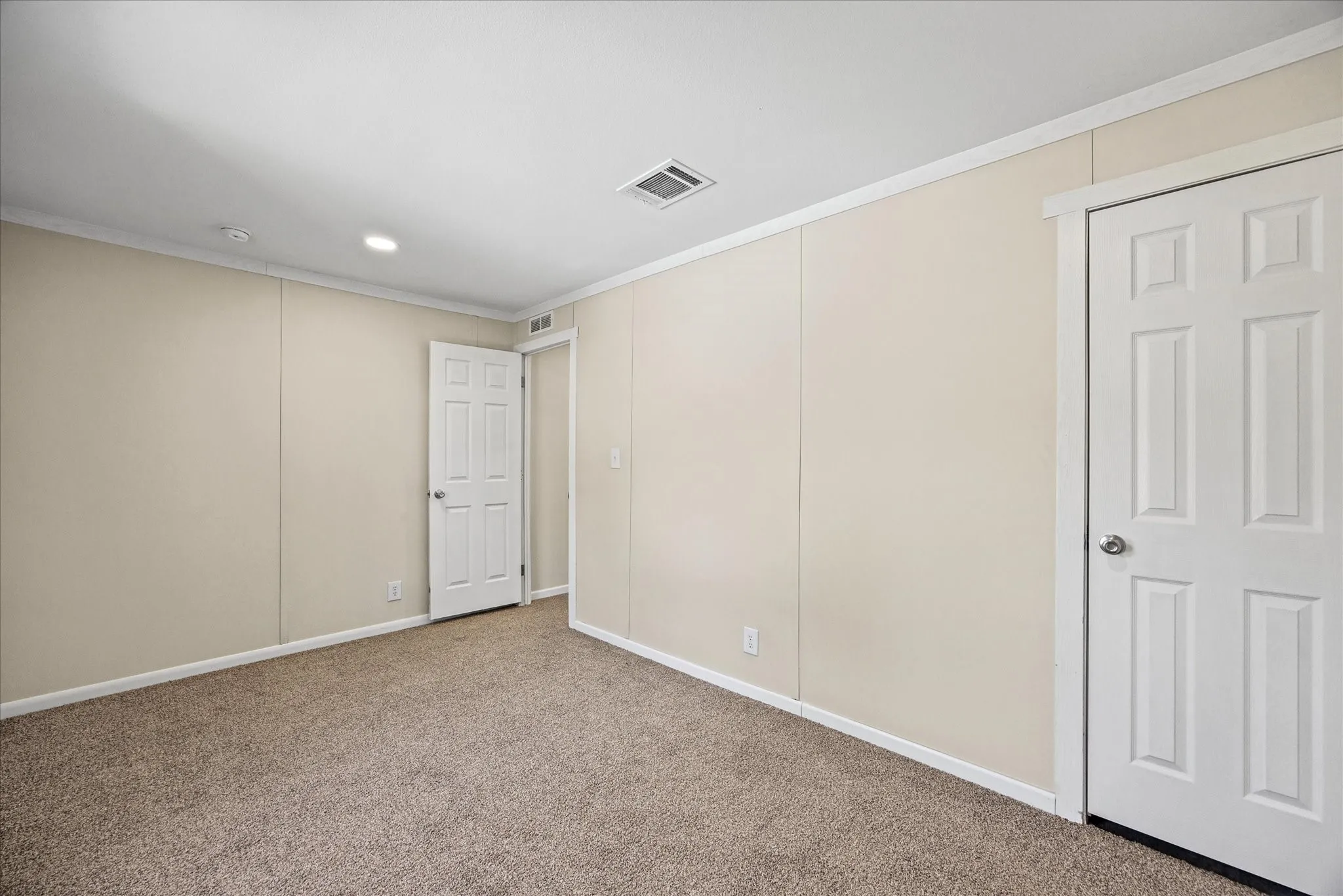 Wall-to-wall carpeting with light-toned walls, white trim, and a six-panel door
