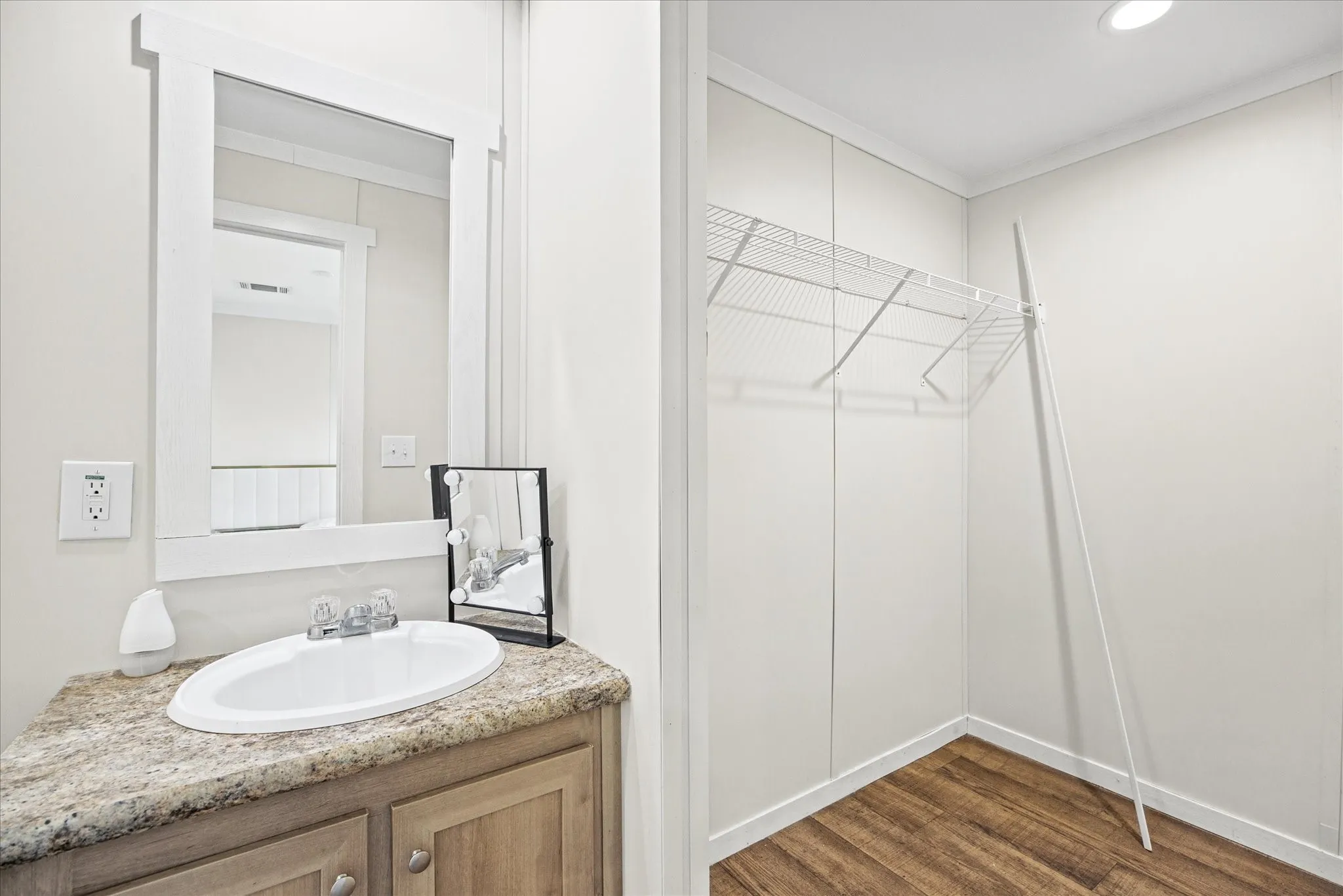 Vanity with an oval undermount sink, a framed mirror, and wood-finish cabinetry