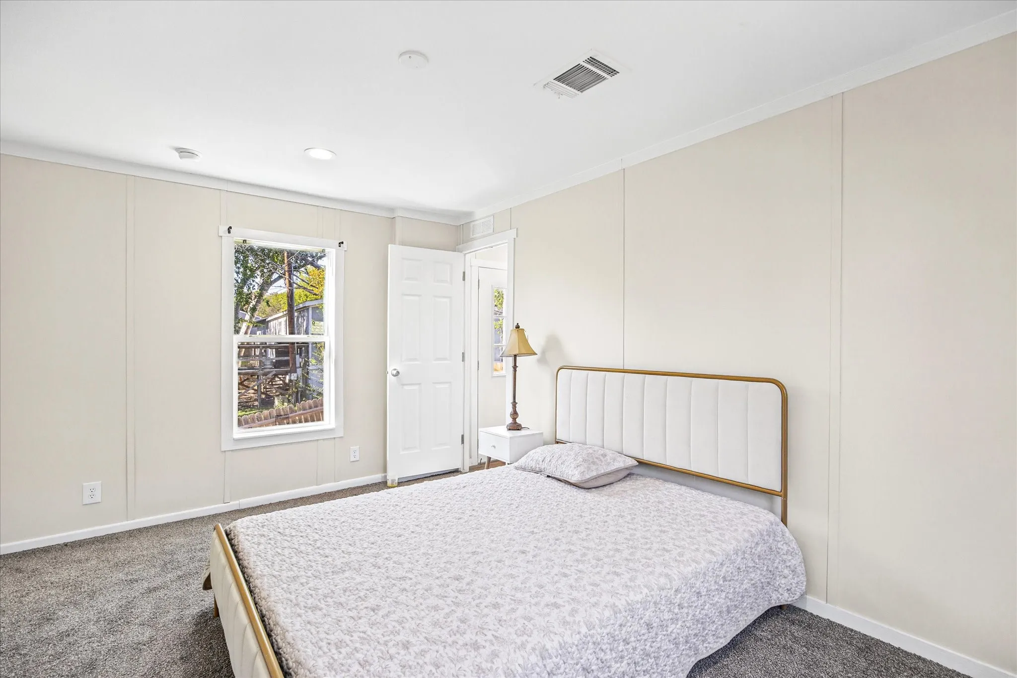Recessed ceiling lighting, paneled walls, gray carpeting, white trim, and a white interior door