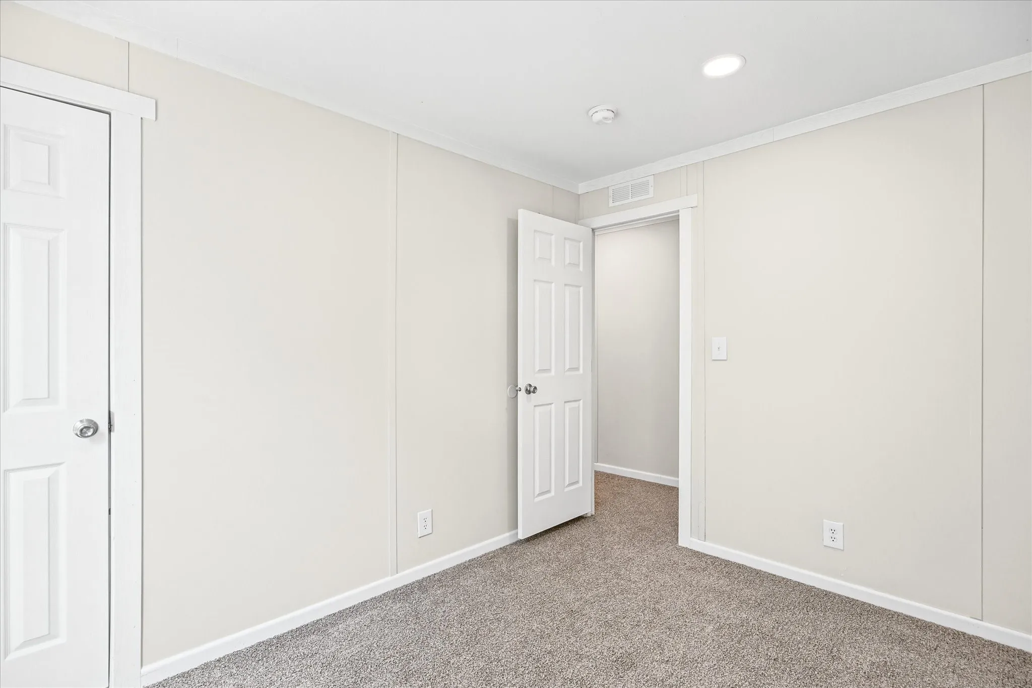 Neutral-toned wall paneling, recessed ceiling lighting, and soft gray carpeting