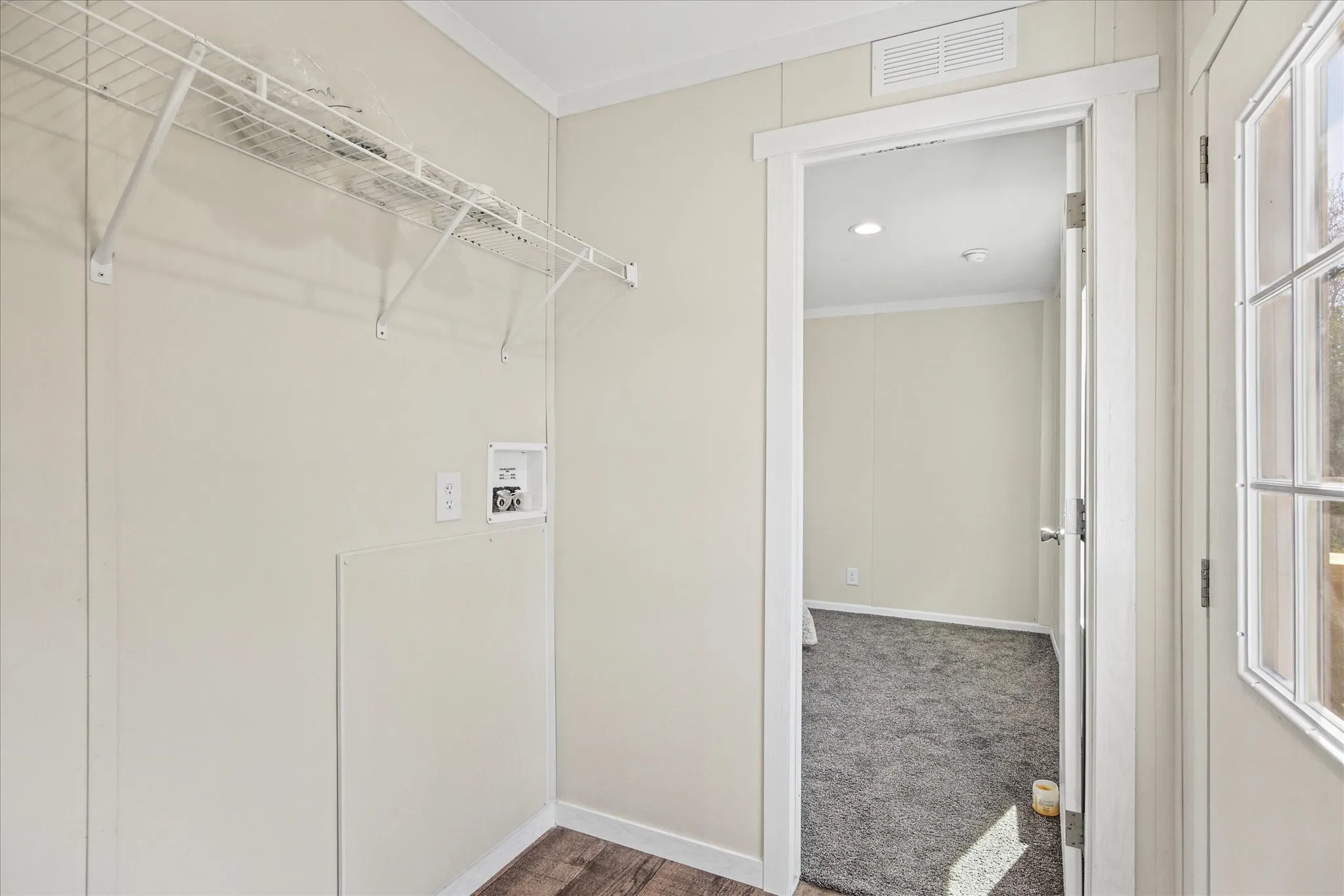 Utility area with wood-finish flooring, white wire shelving, and appliance hookups