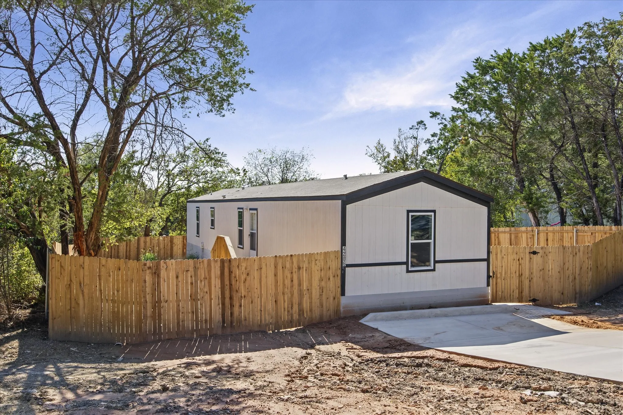 White siding with dark trim, fenced perimeter, and a concrete driveway