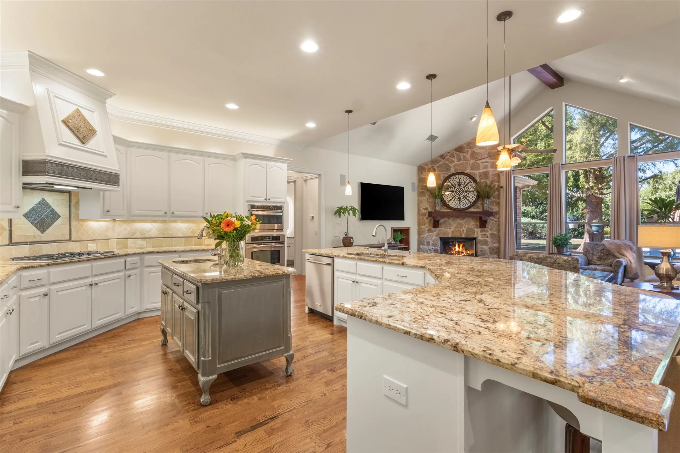 Kitchen features a large island, wood-finish flooring, and white cabinetry