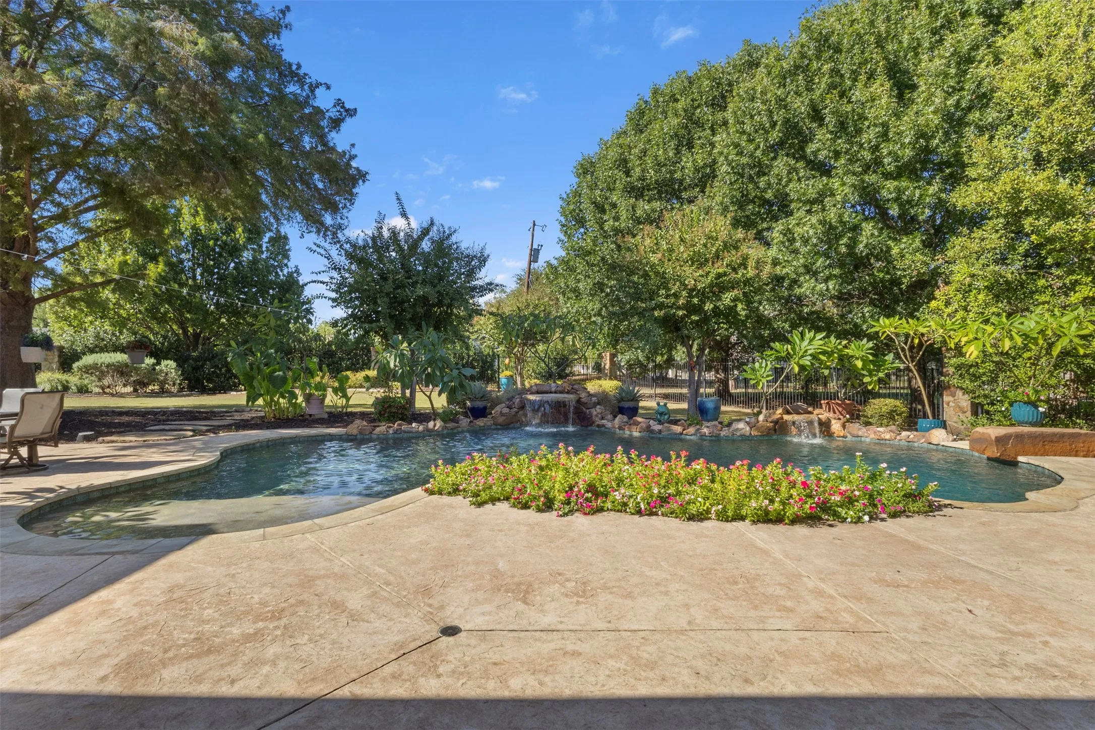 Custom-shaped pool featuring a waterfall and surrounding hardscaping
