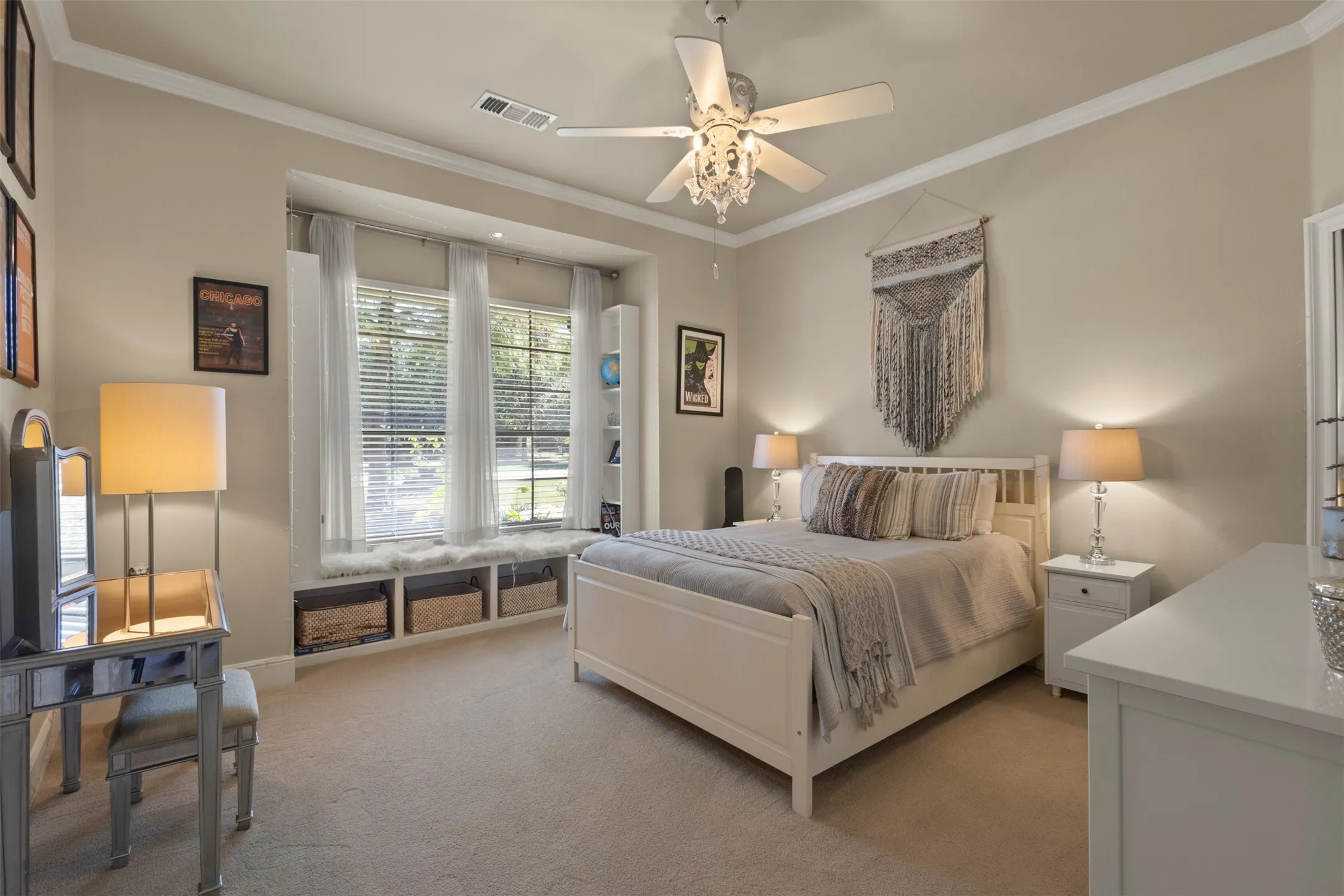 Recessed window bay with built-in storage, crown molding, ceiling fan with chandelier lighting, and neutral wall tones
