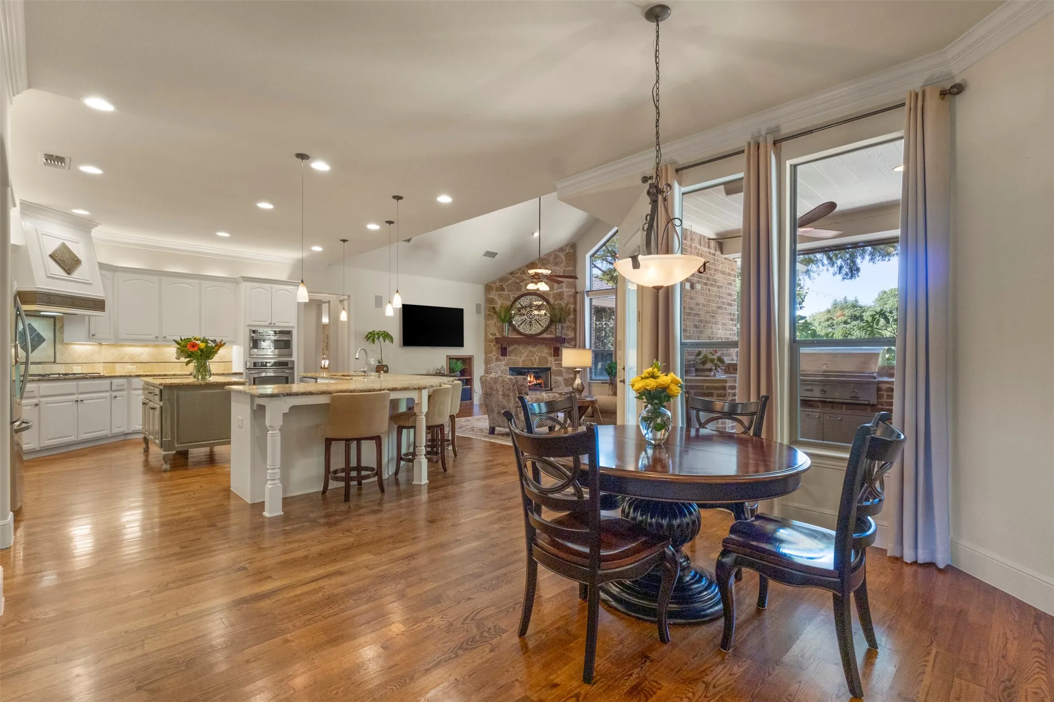 Open concept living space featuring wood-finish flooring, vaulted ceilings, and large windows