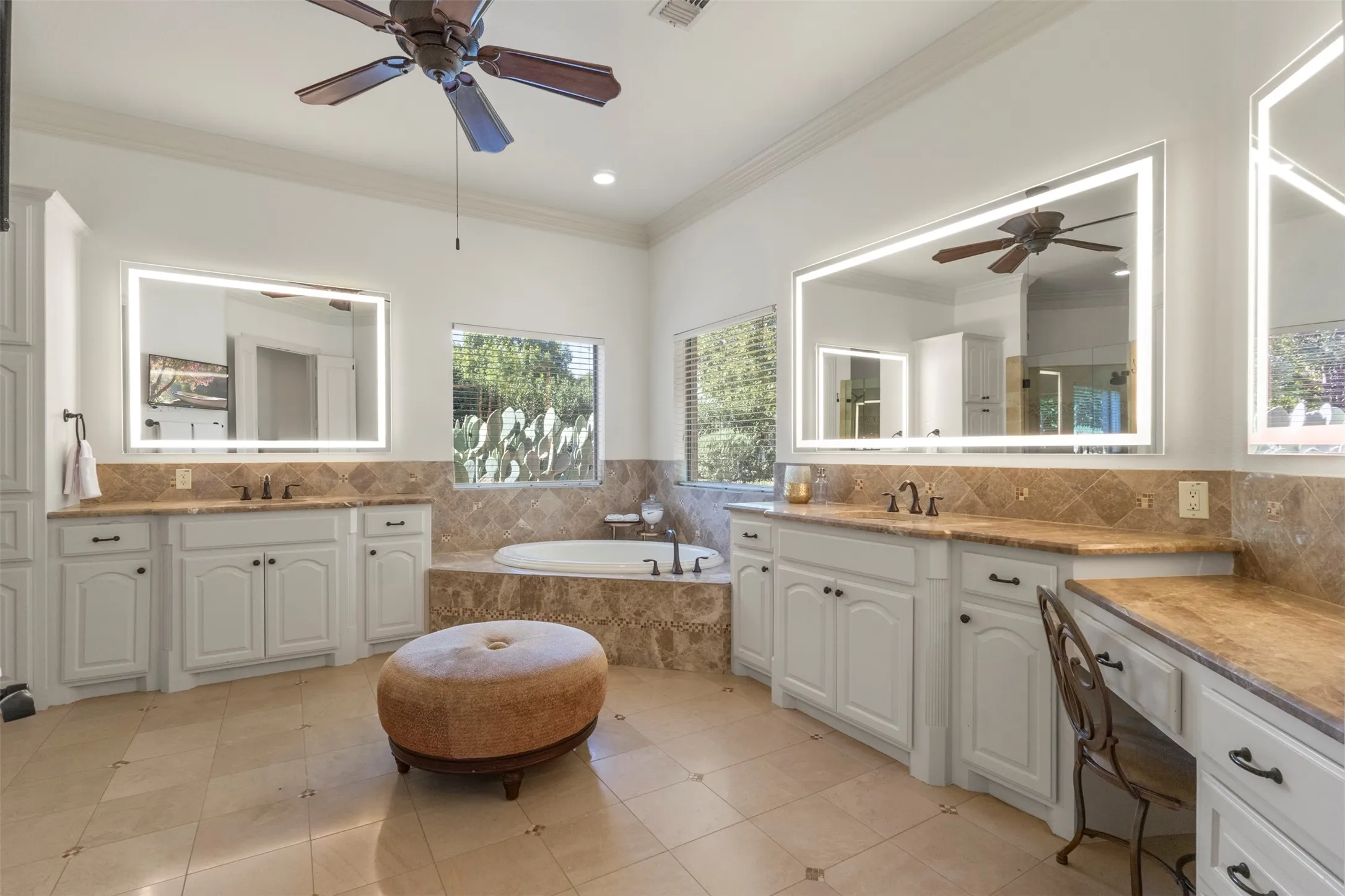 Dual vanities with integrated lighting mirrors, built-in soaking tub, tile flooring, and a dedicated vanity area