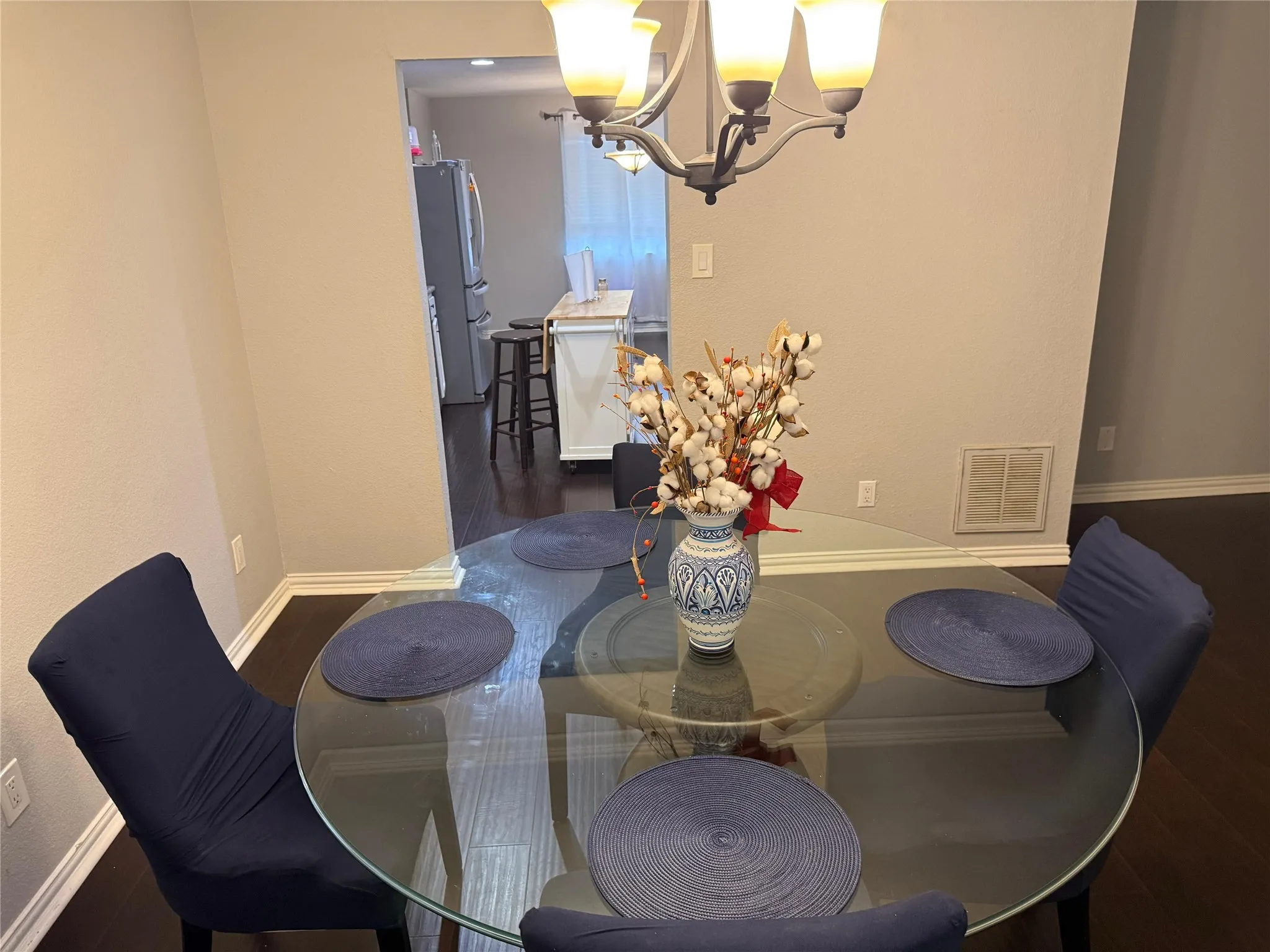 Recessed archway entry leading to a kitchen with a white island, dark wood-finish flooring, and a multi-light chandelier
