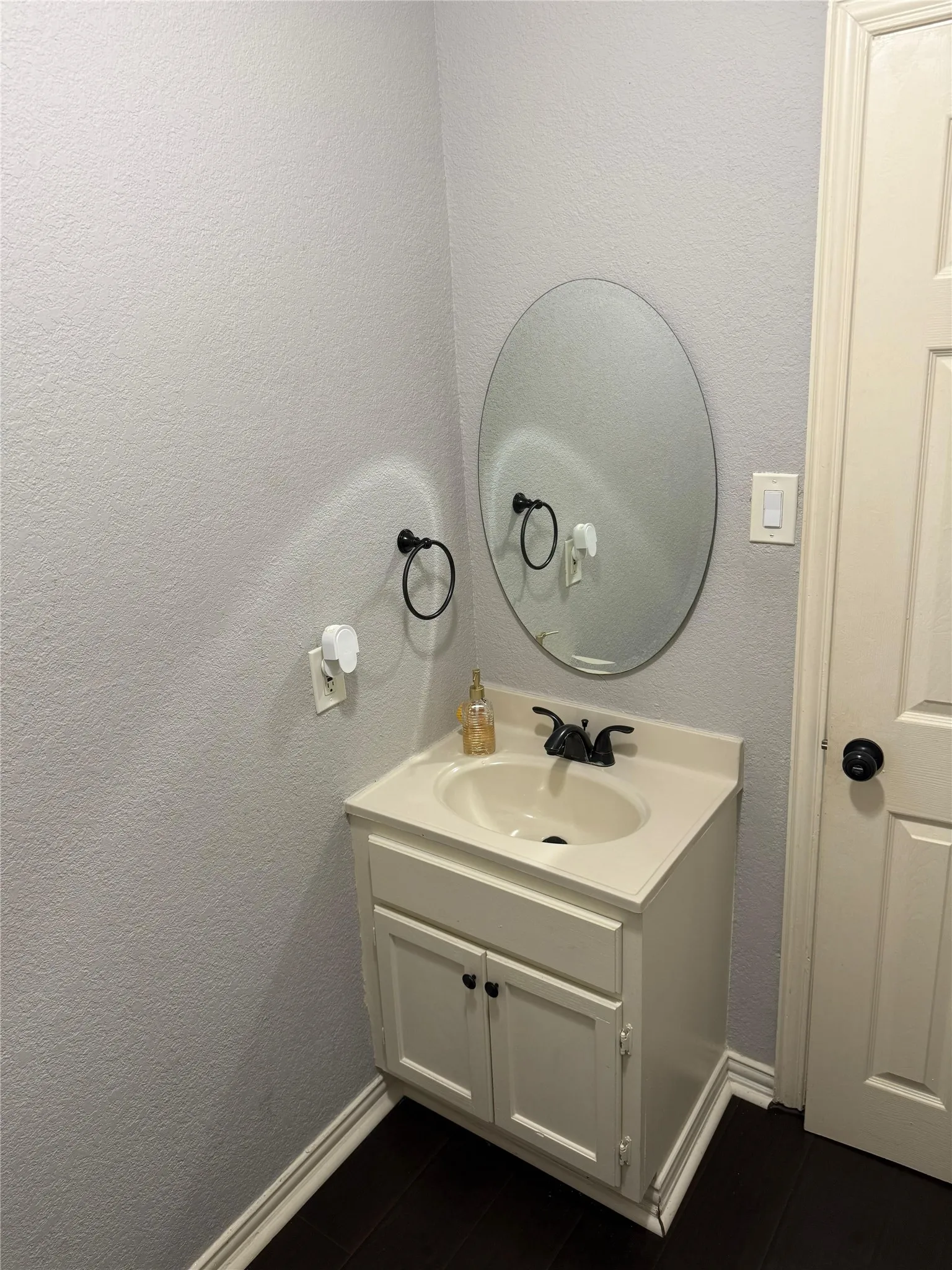 Bathroom vanity featuring a single-basin sink, dark-finish faucet, and coordinating cabinet hardware