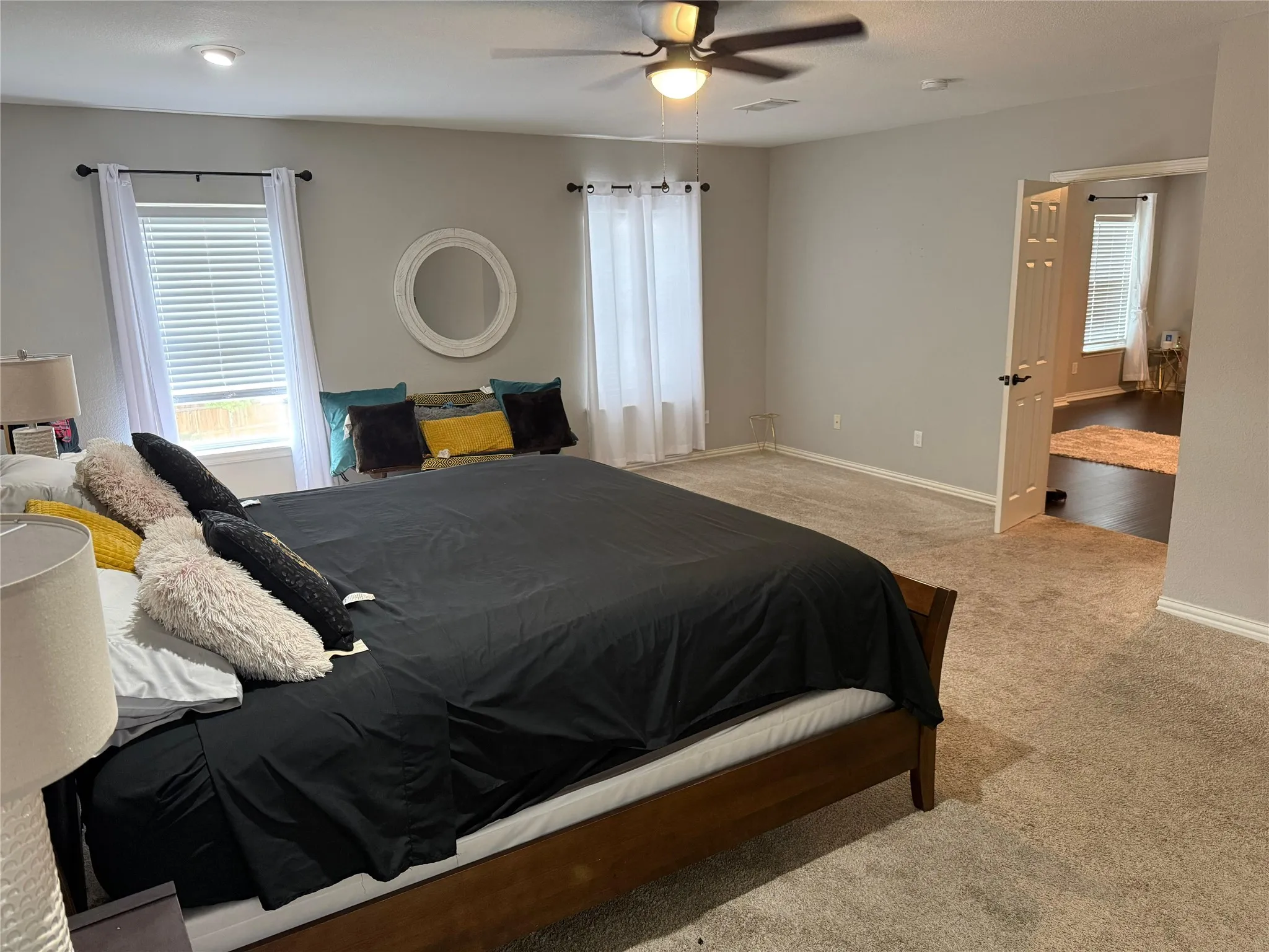 Spacious room with plush carpeting, neutral wall tones, and multiple windows