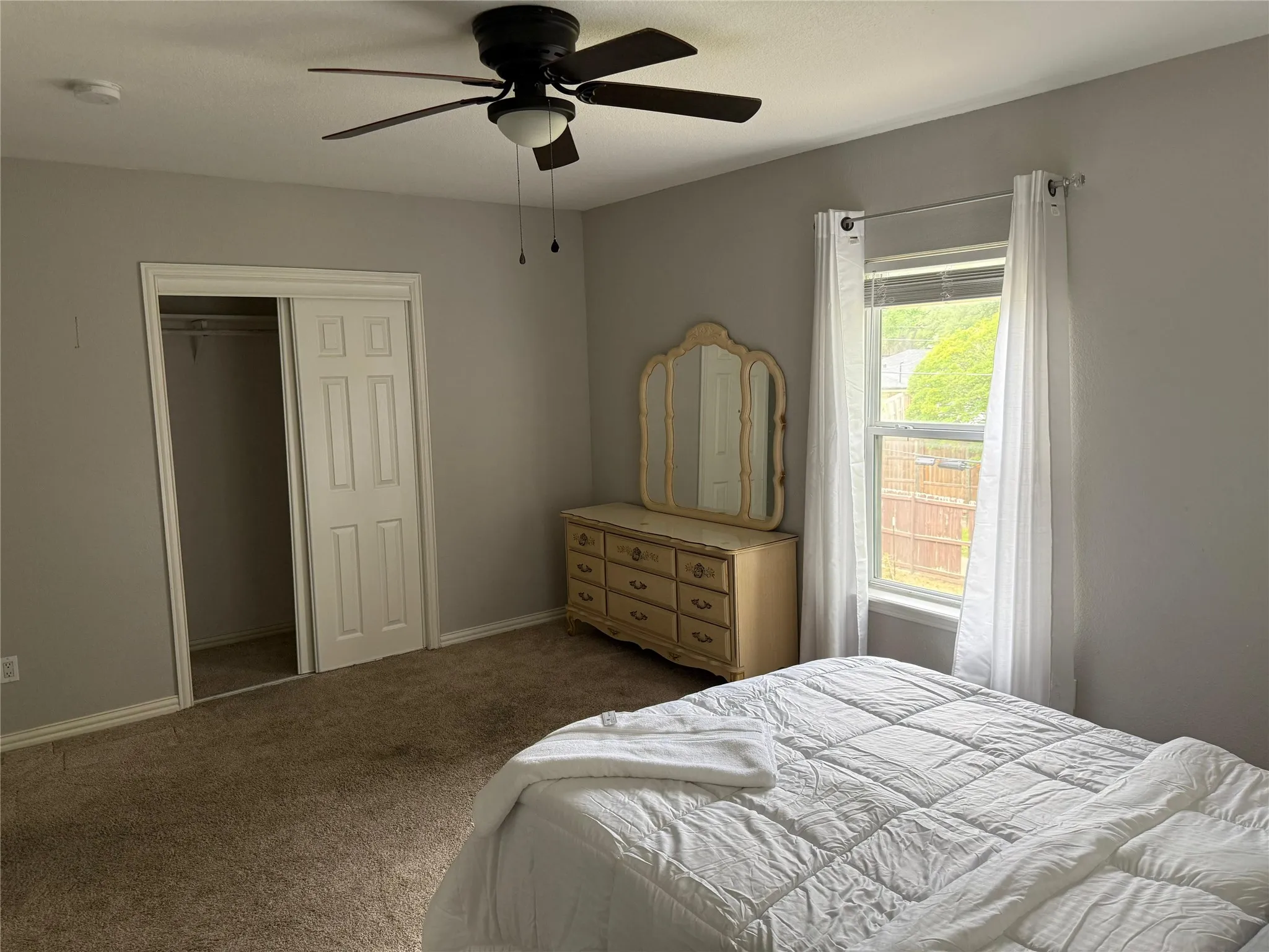 Ceiling fan with integrated lighting, carpeted flooring, window with blinds, and bi-fold closet doors
