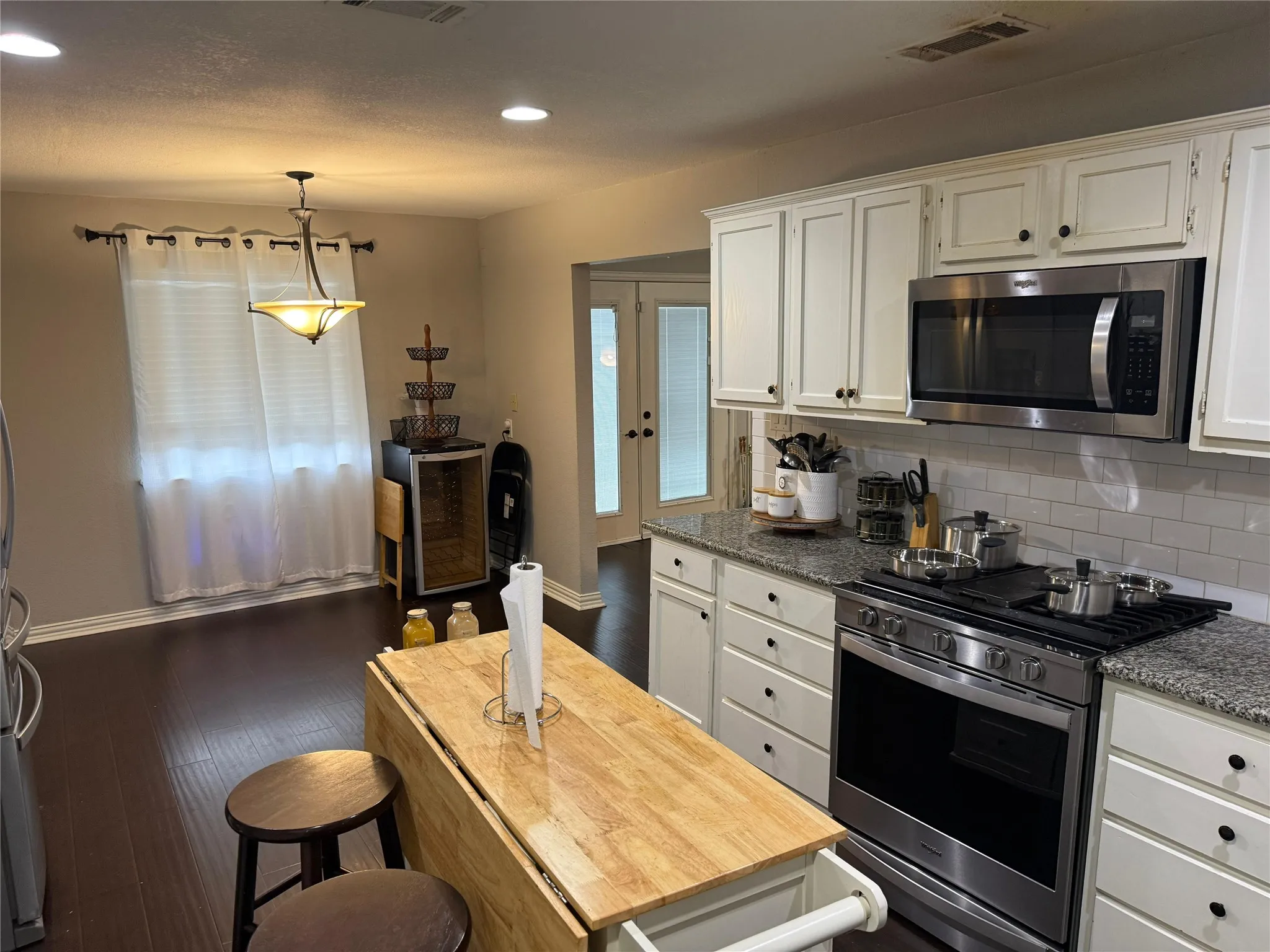 Kitchen featuring white cabinetry, stainless steel appliances, granite countertops, and subway tile backsplash