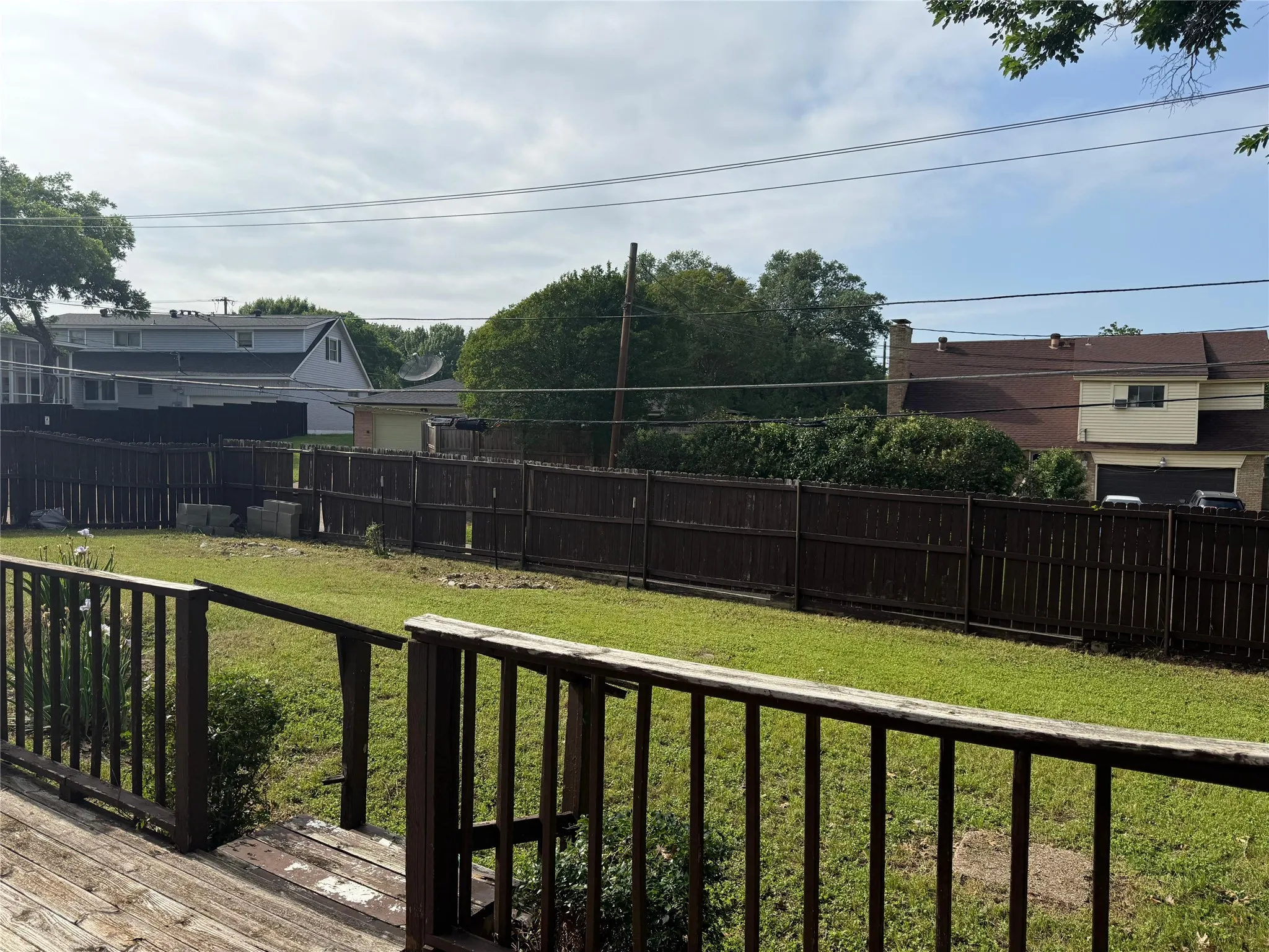 Expansive backyard featuring a manicured lawn, full privacy fencing, and wood-finish decking