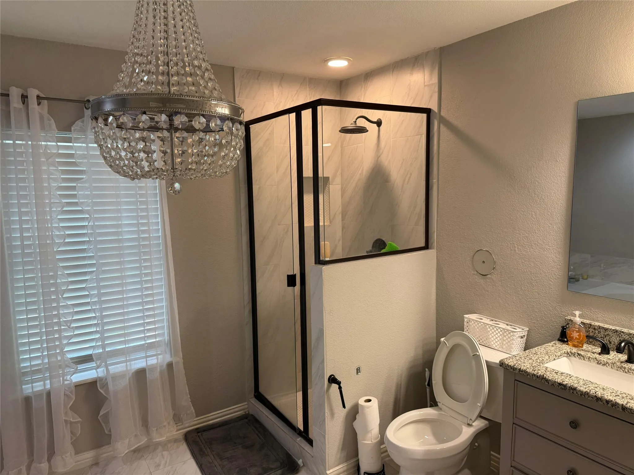 Walk-in shower with dark-framed glass enclosure, tile surround, and rainfall showerhead