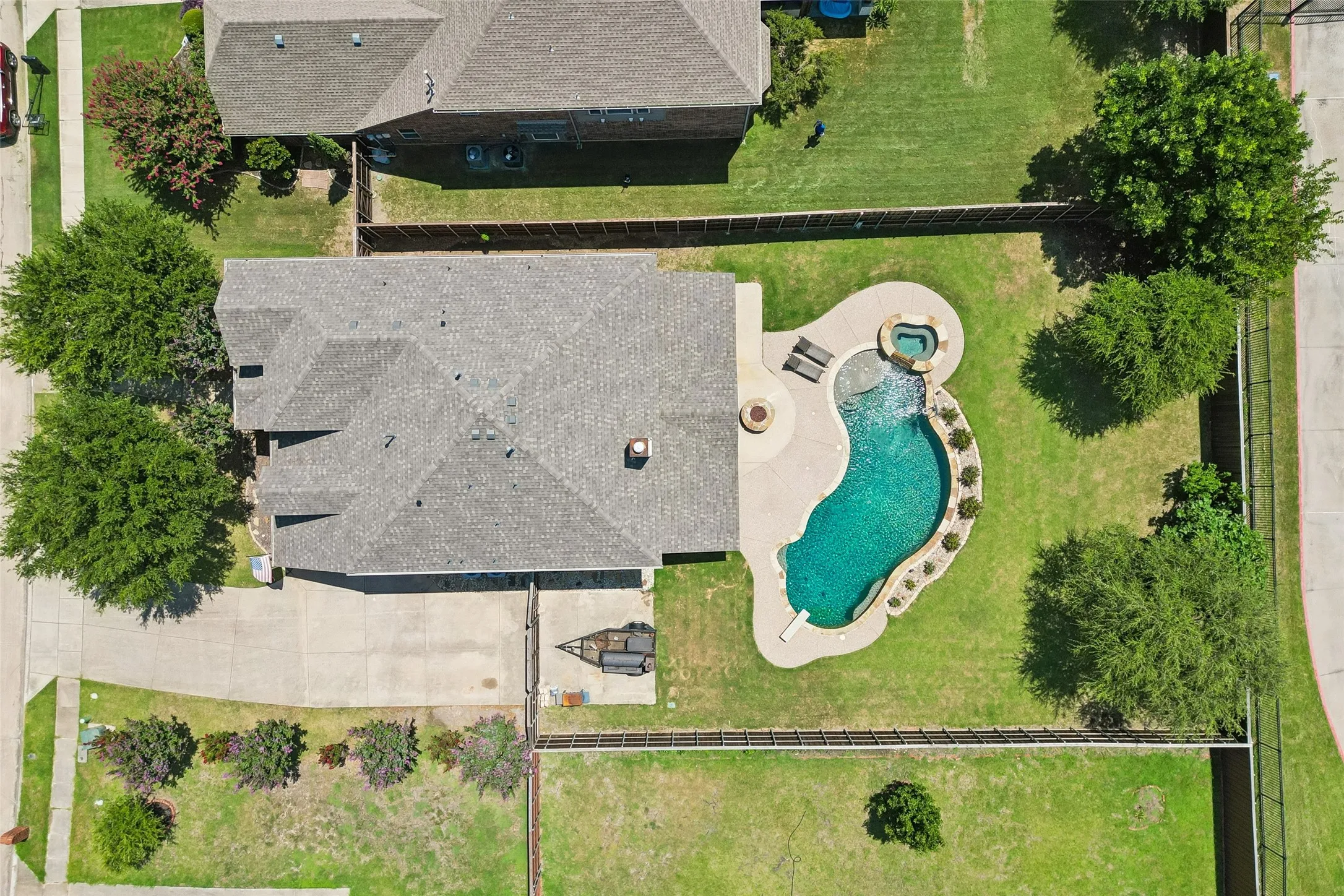 Expansive backyard featuring a freeform swimming pool, integrated spa, and concrete decking
