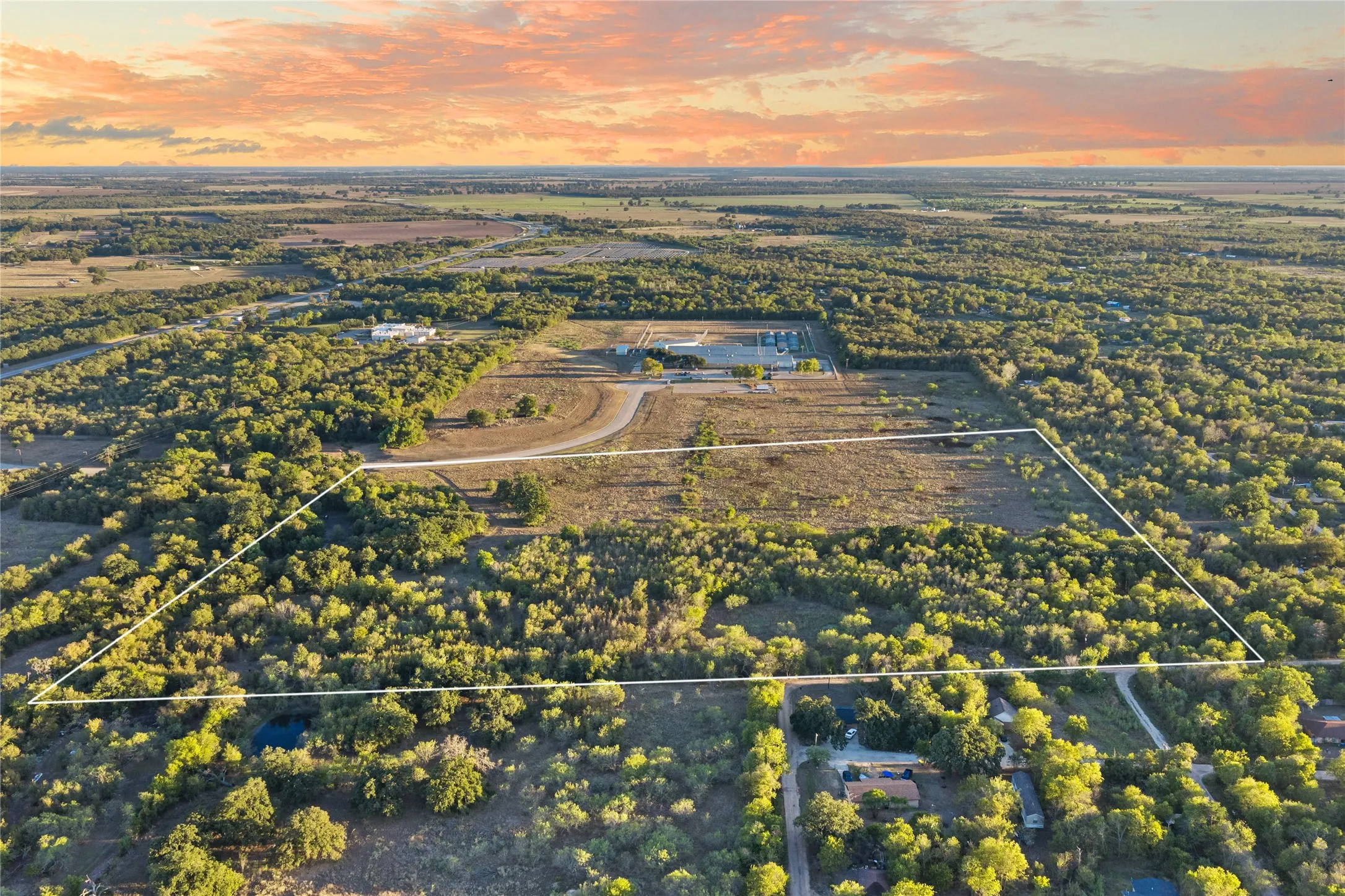 Expansive land parcel featuring a mix of cleared and wooded areas, with a visible access road