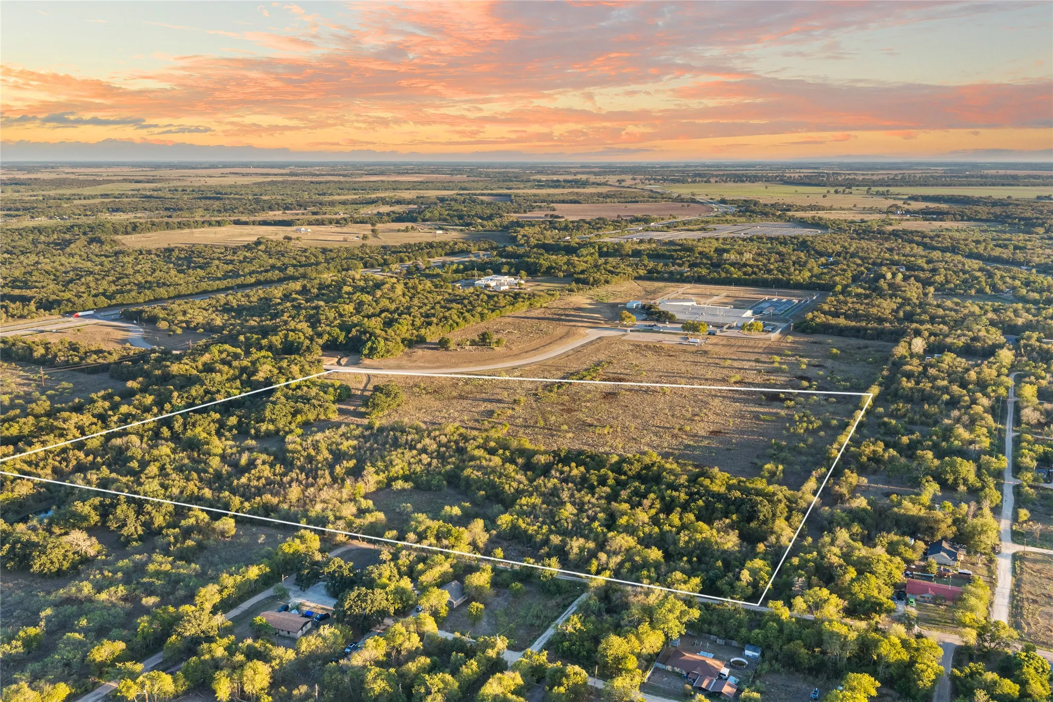 Expansive undeveloped land featuring a mix of open areas and mature trees, surrounded by additional undeveloped parcels