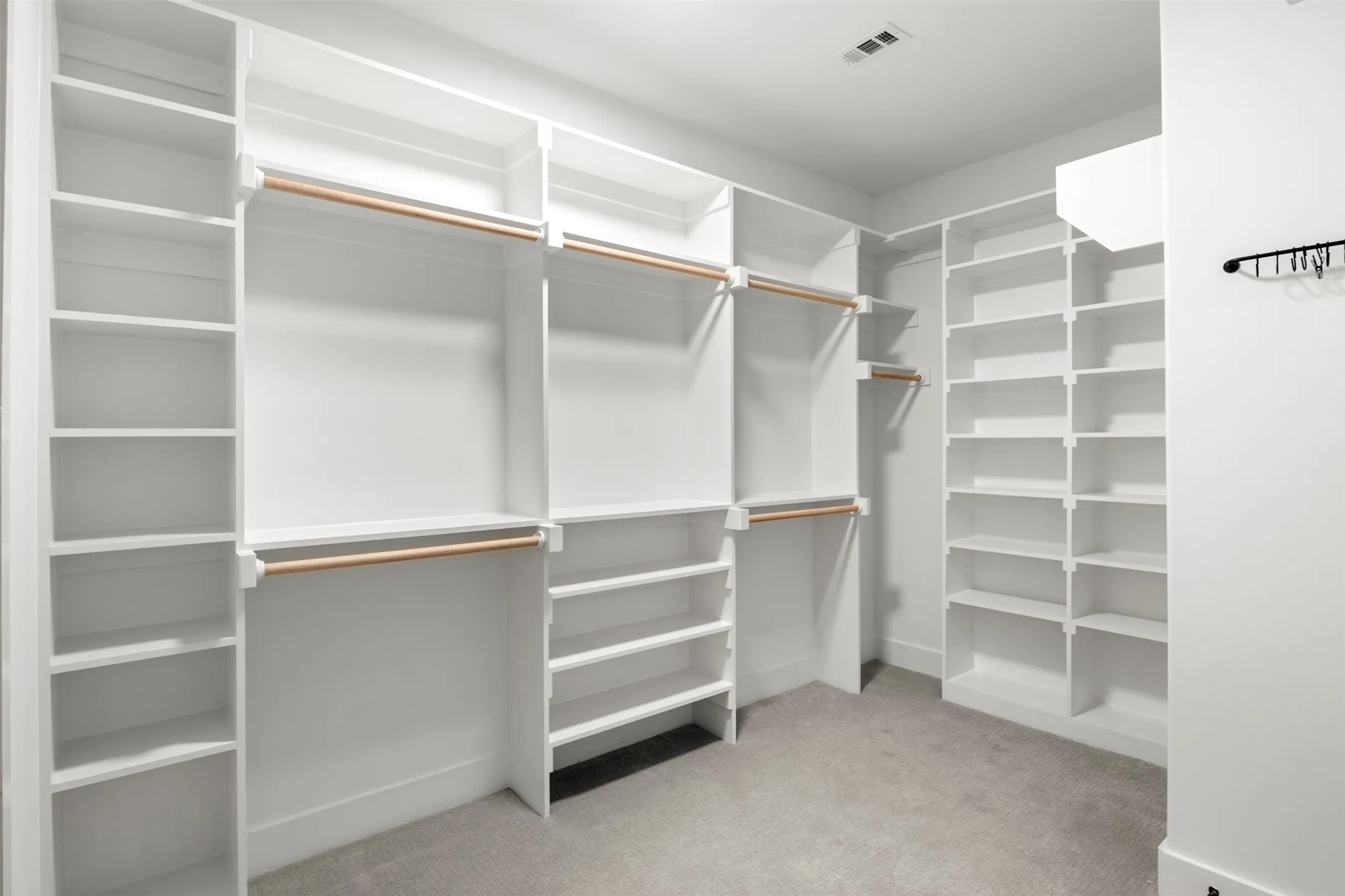 Spacious primary closet with extensive built-in shelving, hanging space and direct laundry access.
