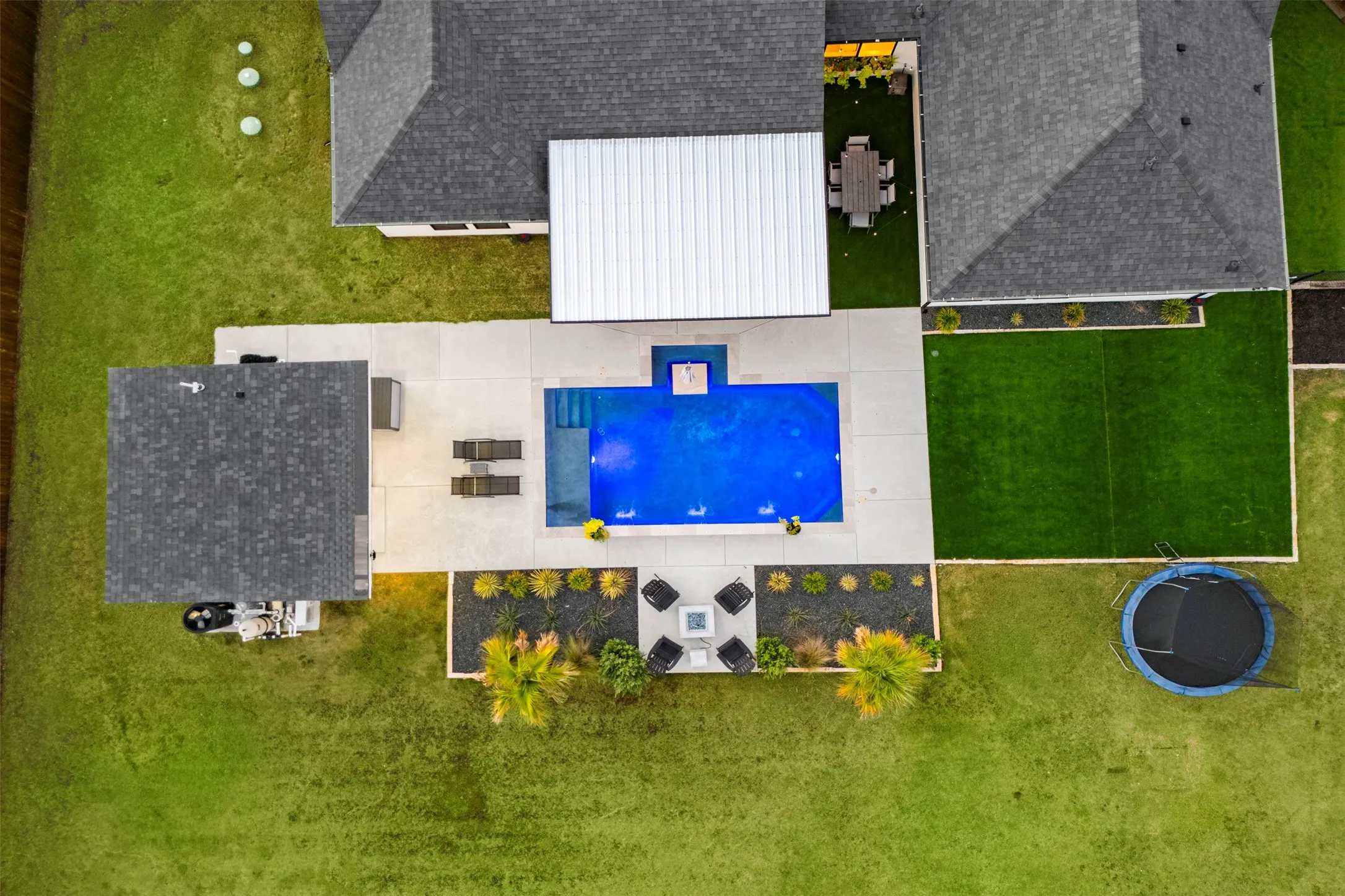 A clear view of the pool, covered patio, separate pool house and backyard layout.