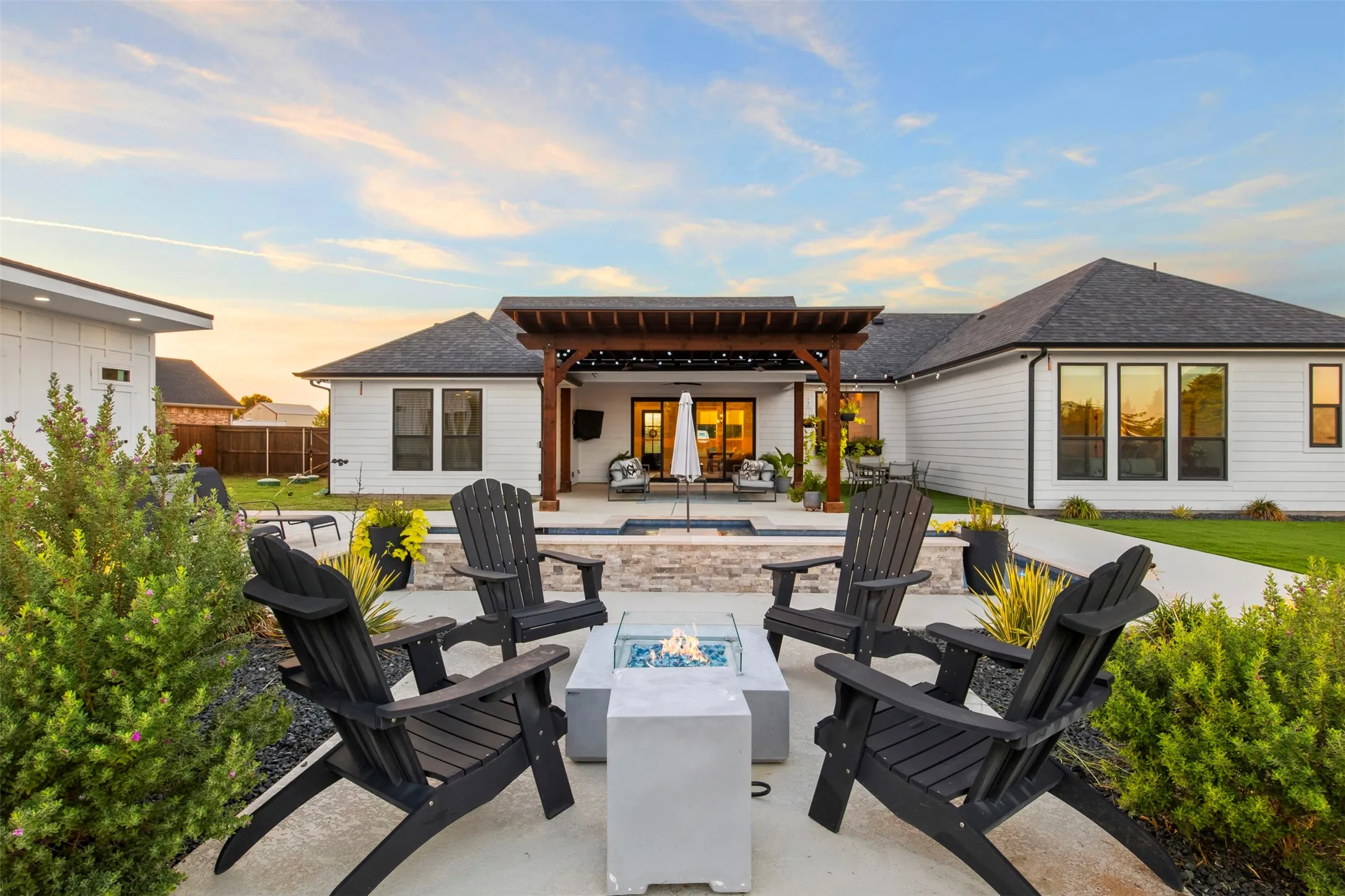Dedicated fire-pit seating area beside the pool and landscaped grounds.