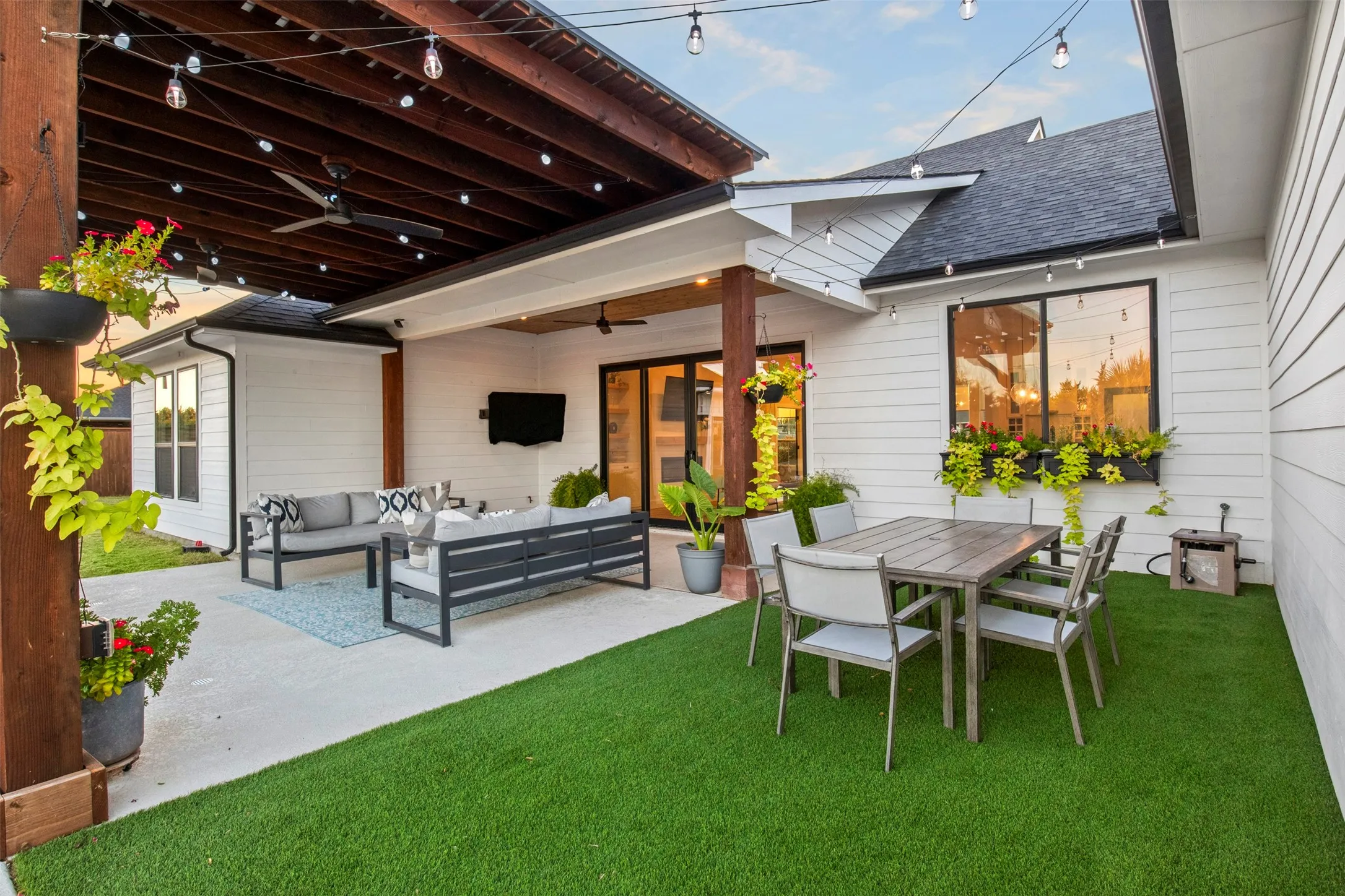 Poolside entertaining is steps from the covered patio and outdoor seating areas with turf underfoot and café lighting overhead.